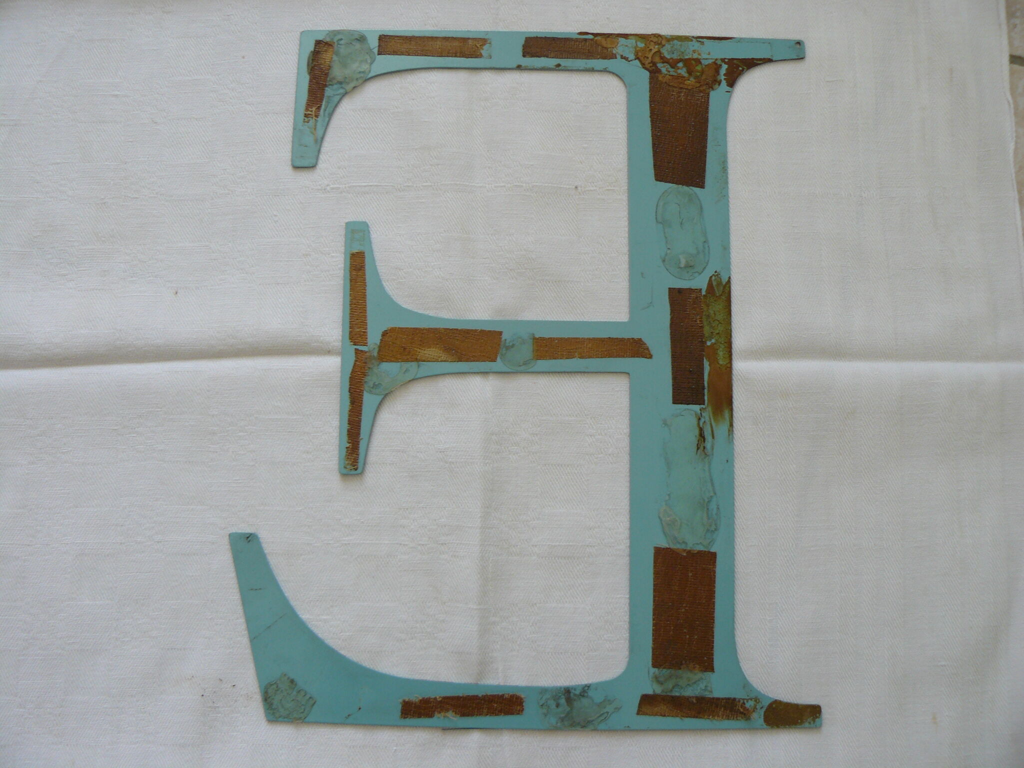 Old letter E painted metal sign