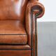 Large sheepskin wingback chair with black piping and decorative nails