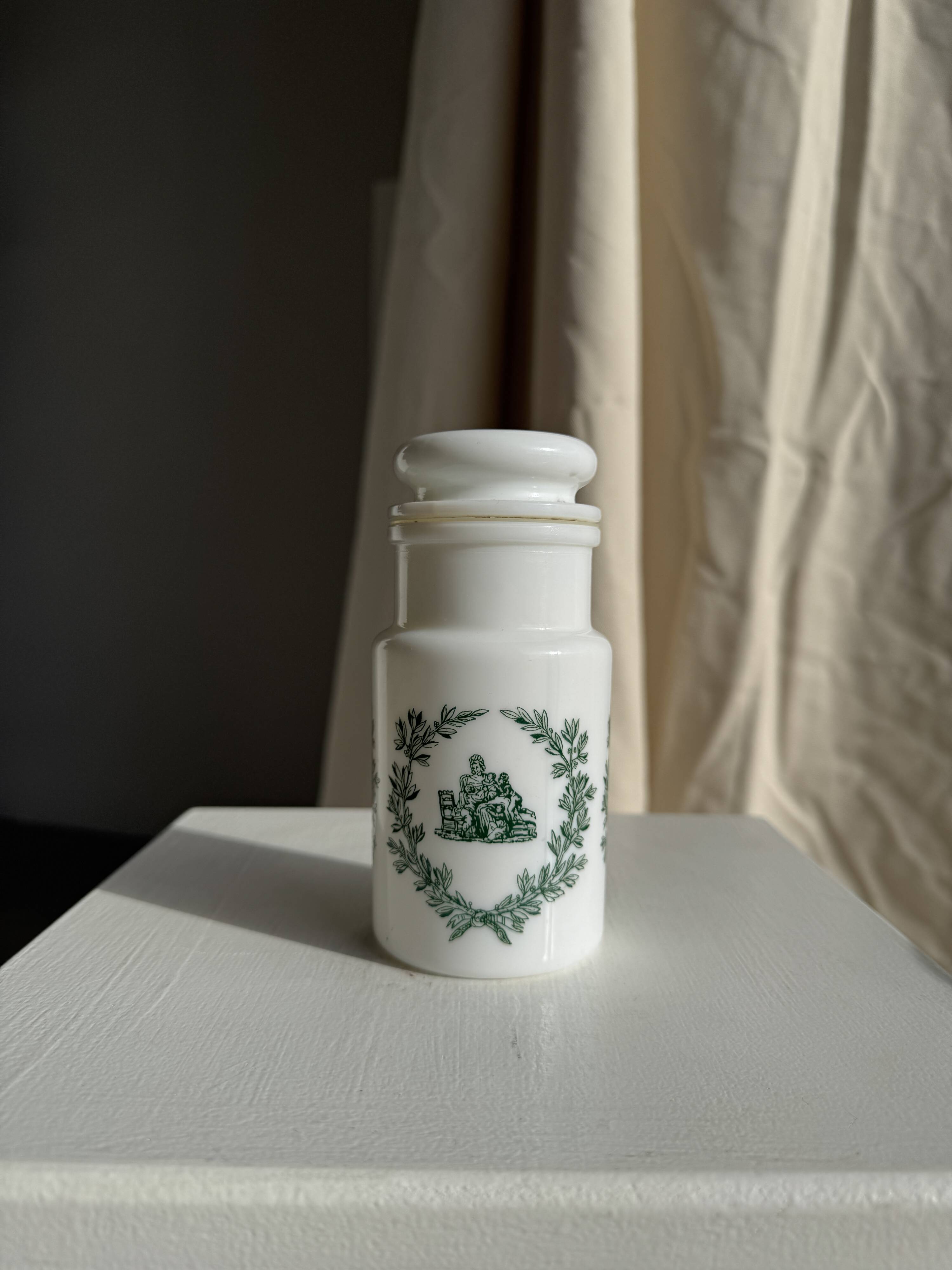 A pair of white glass bottles with Italian green patterns.