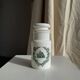 A pair of white glass bottles with Italian green patterns.