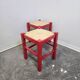 Tabouret en bois rouge avec assise en paille tressée.