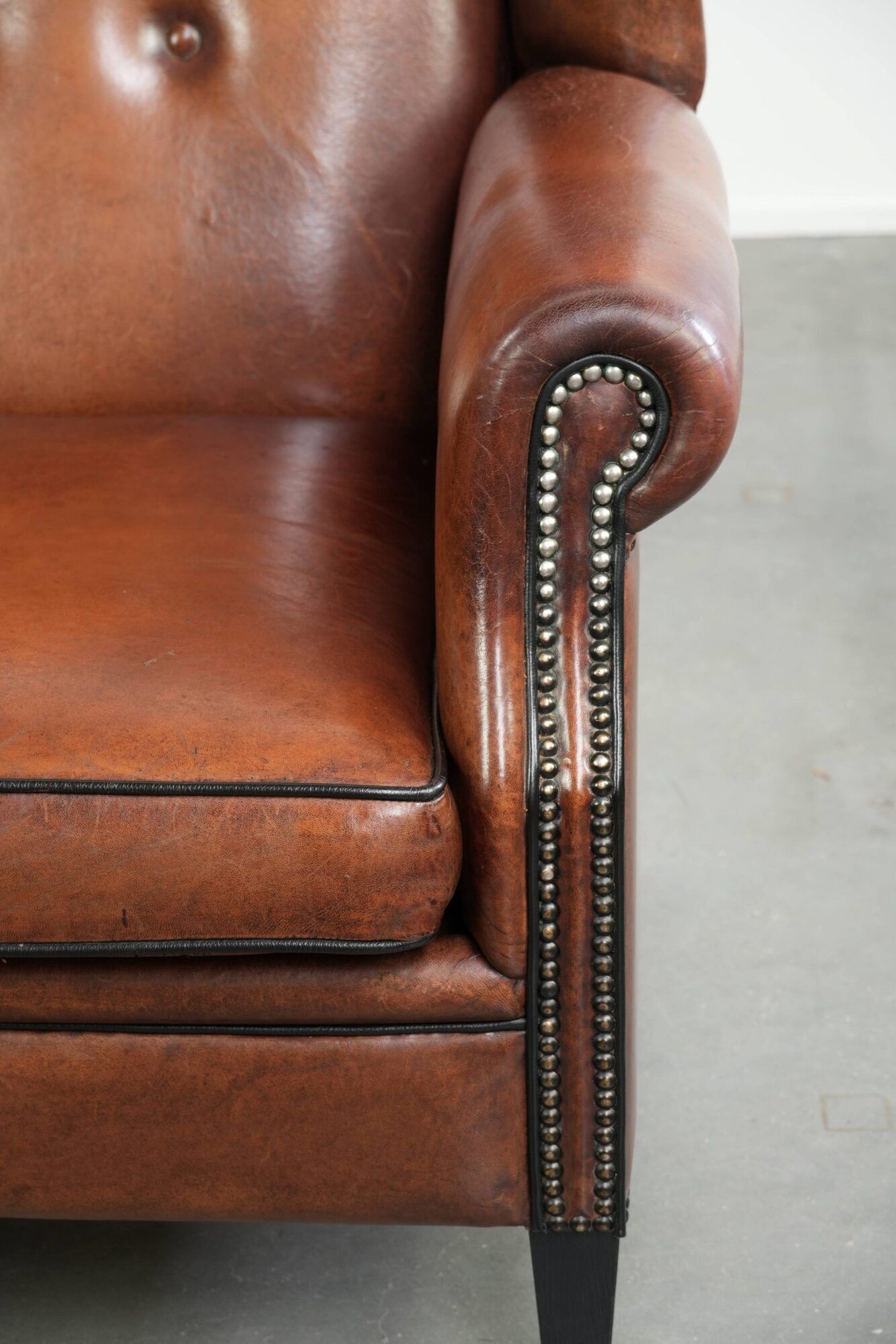 Sheepskin wingback armchair in a warm cognac colour with refined nailhead trim