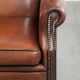 Sheepskin wingback armchair in a warm cognac colour with refined nailhead trim