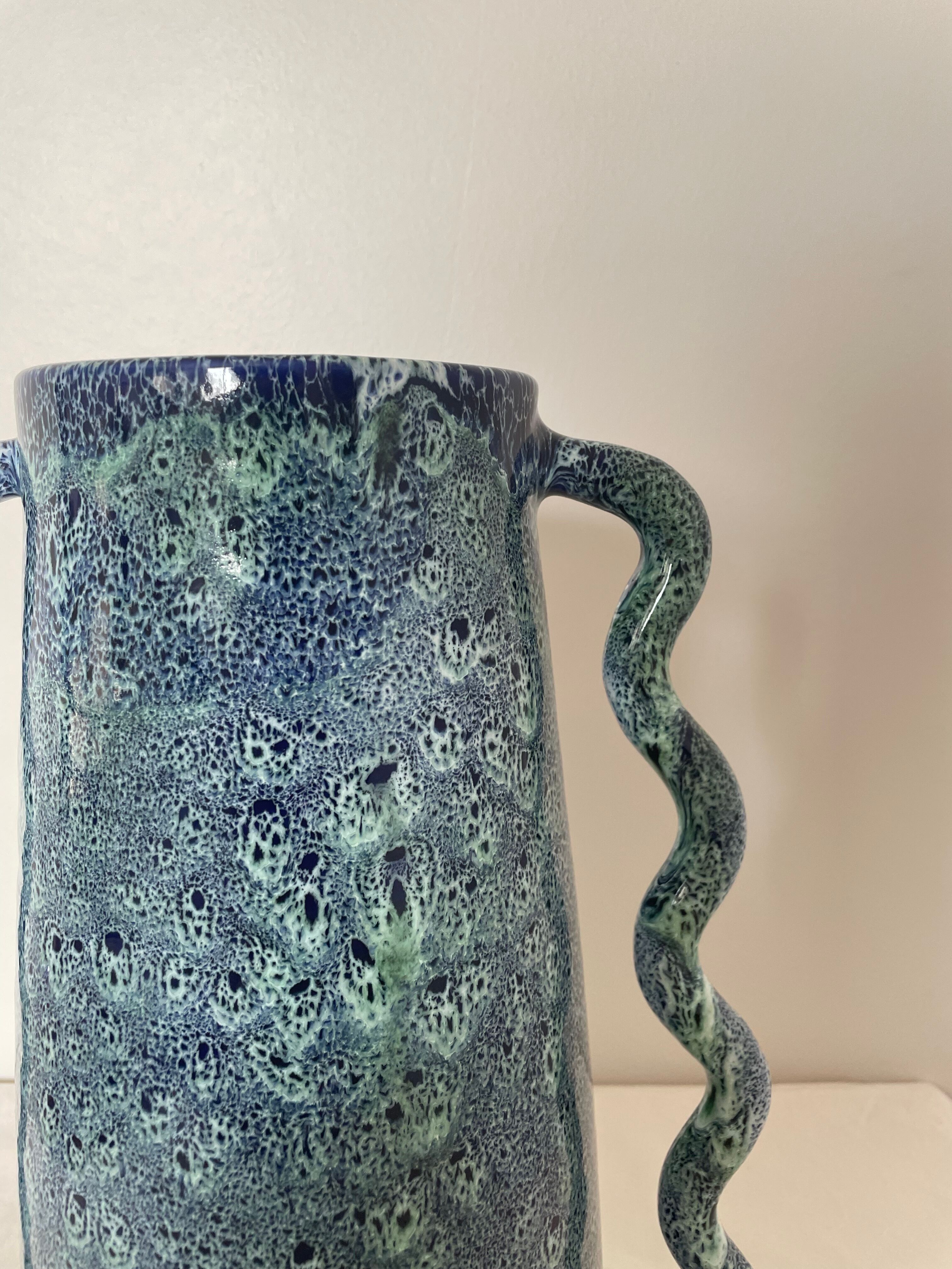 Blue-green ceramic vase with abstract wavy handles