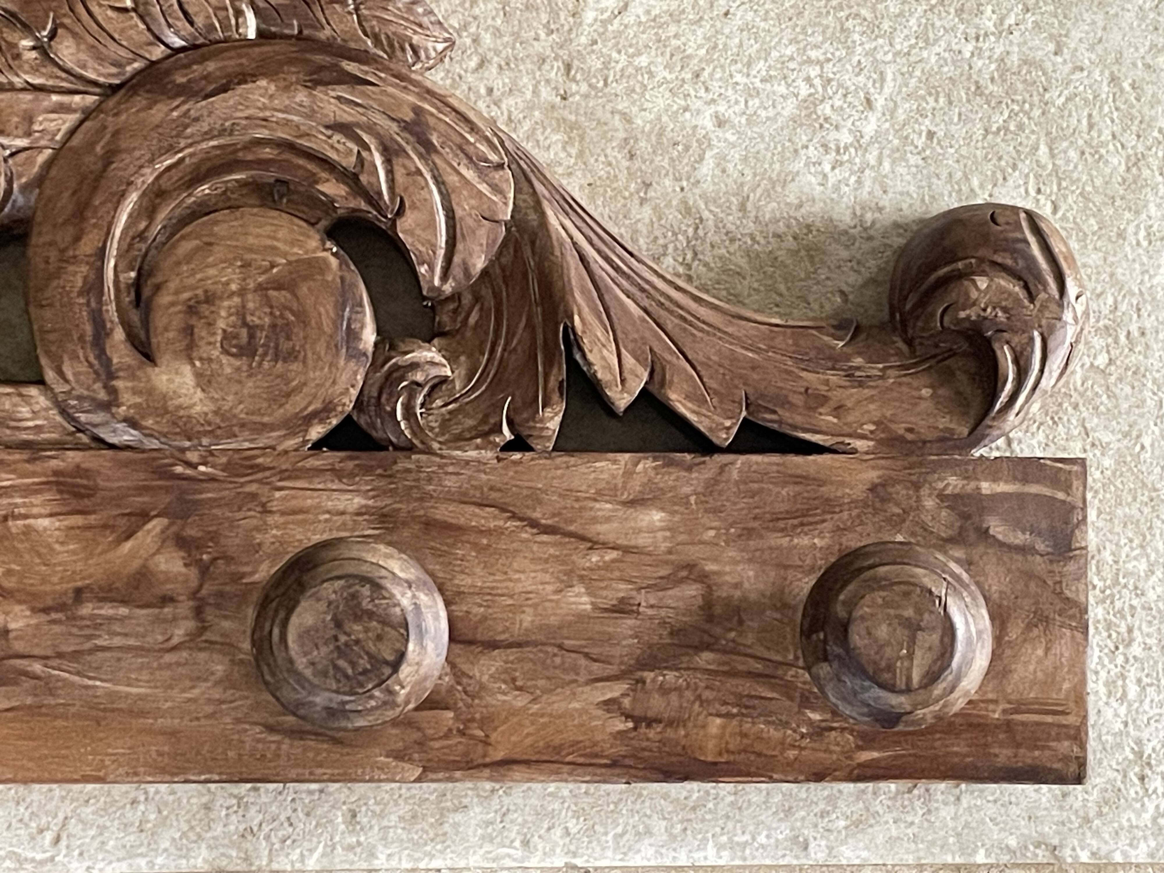 Wall-mounted coat rack on a carved wooden pediment