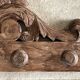 Wall-mounted coat rack on a carved wooden pediment