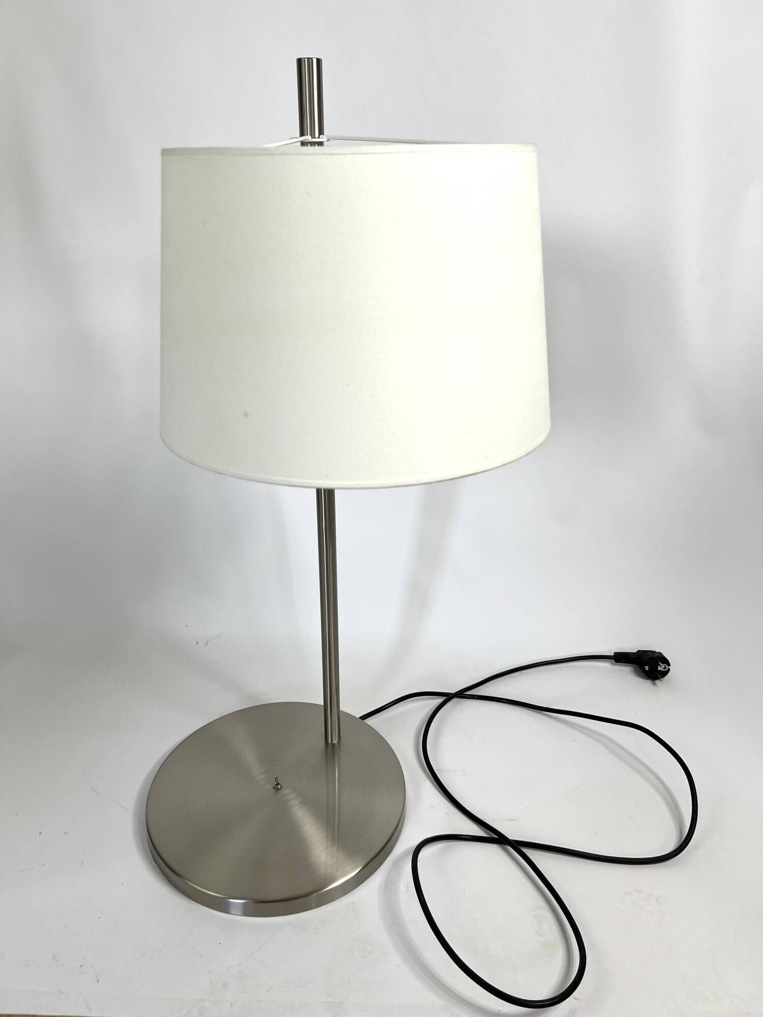 Large brushed metal table lamp with an ecru shade.