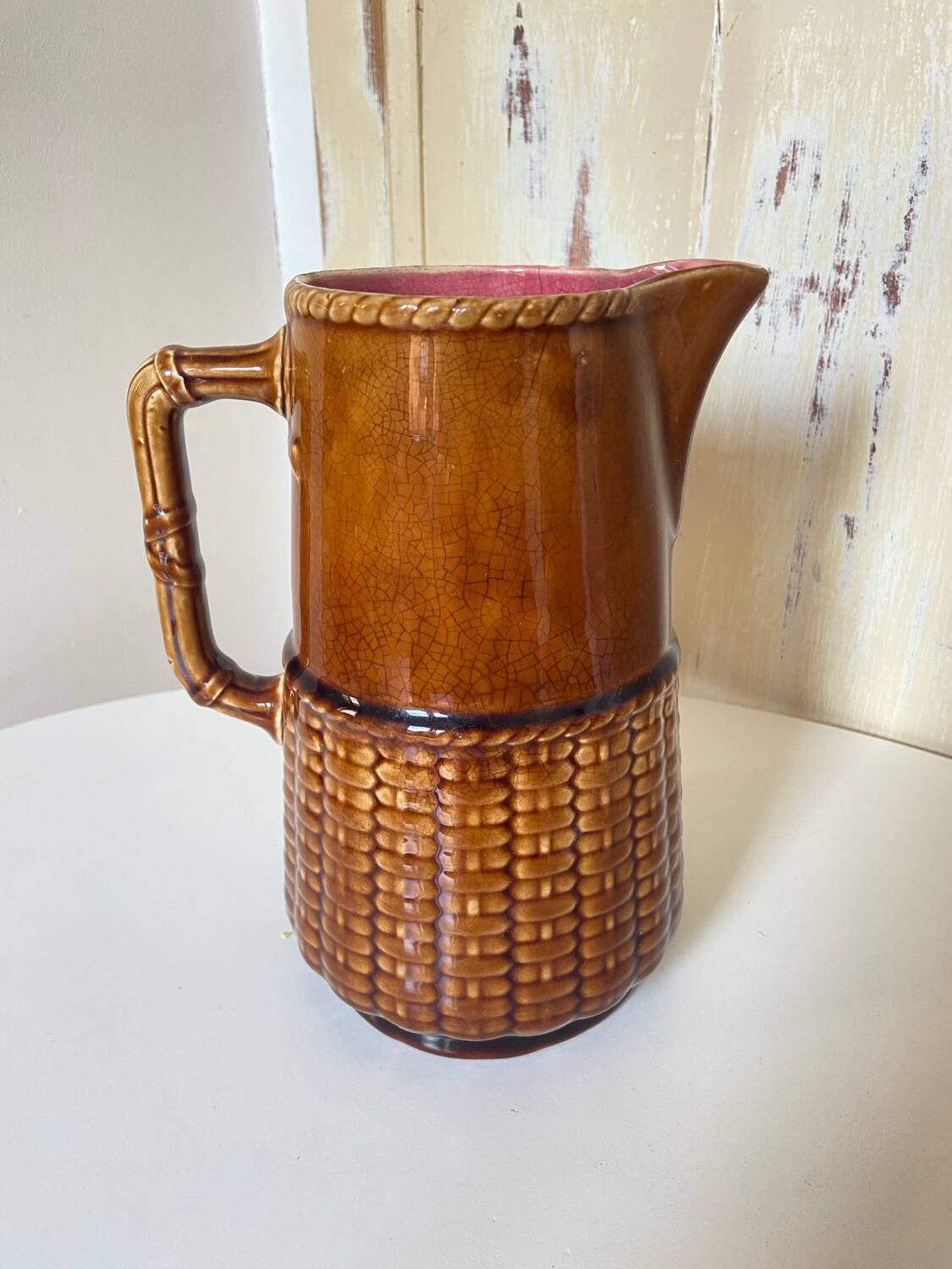 Antique vintage ceramic pitcher or jug from Sarreguemines, France. Brown with a pink interior, imitation basket.
