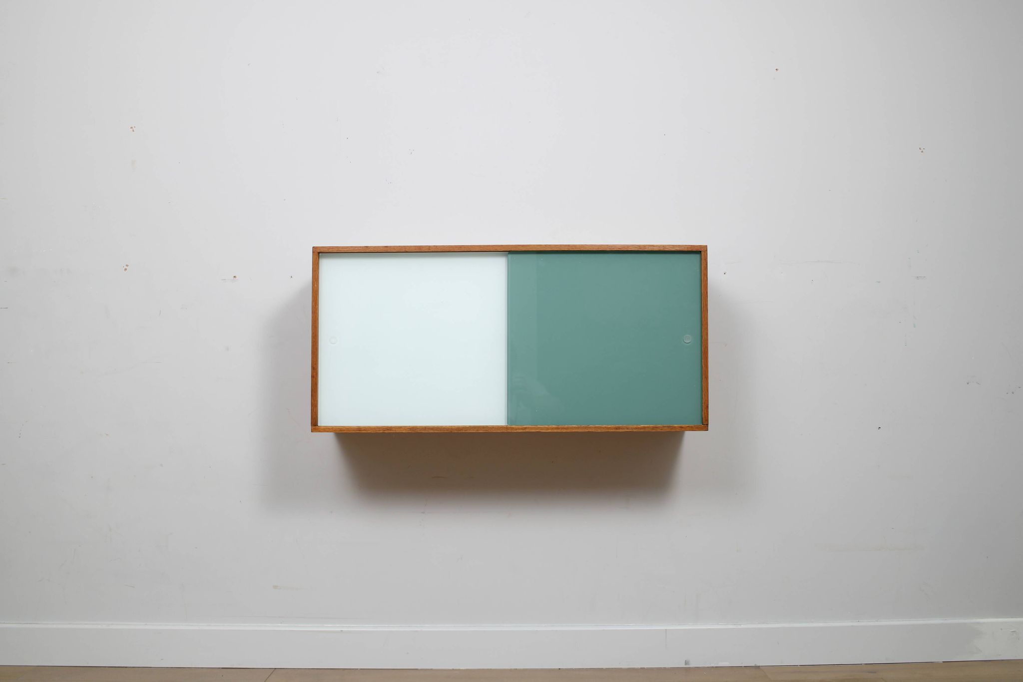 A vintage mid century wall hung bookcase/cabinet with glass sliding doors