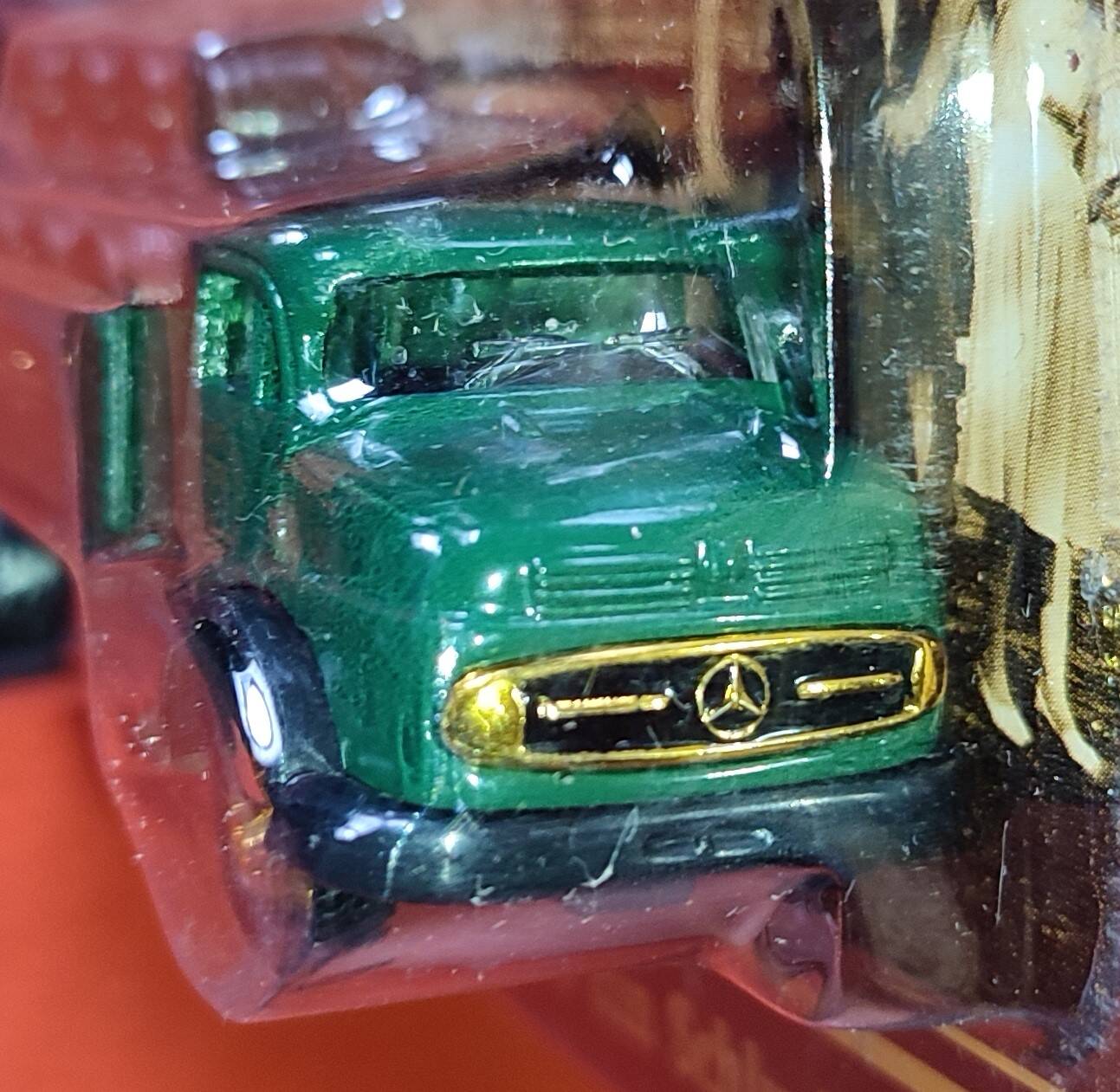 Mercedes flatbed containing drums pulling 1 trailer carrying 1 covered vehicle