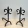 Pair of wrought iron fire dogs with fleur-de-lis.