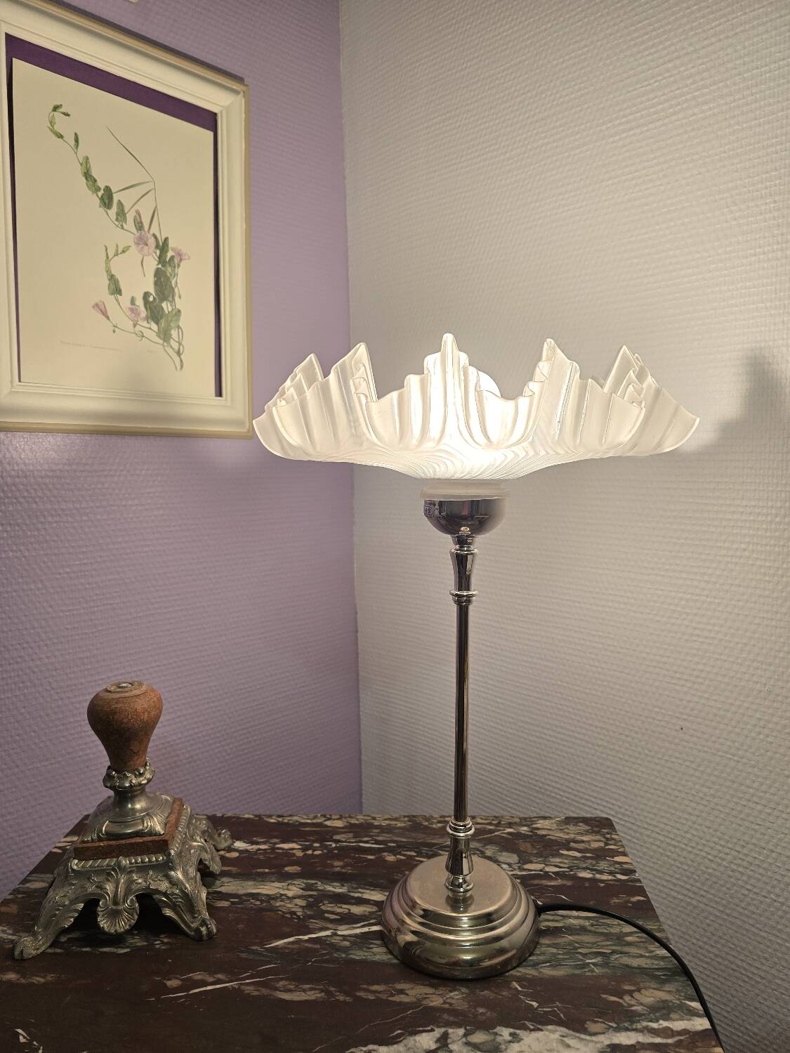 Table lamp with a silver base and a scalloped shade.