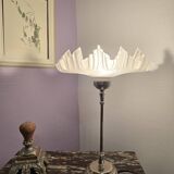 Table lamp with a silver base and a scalloped shade.