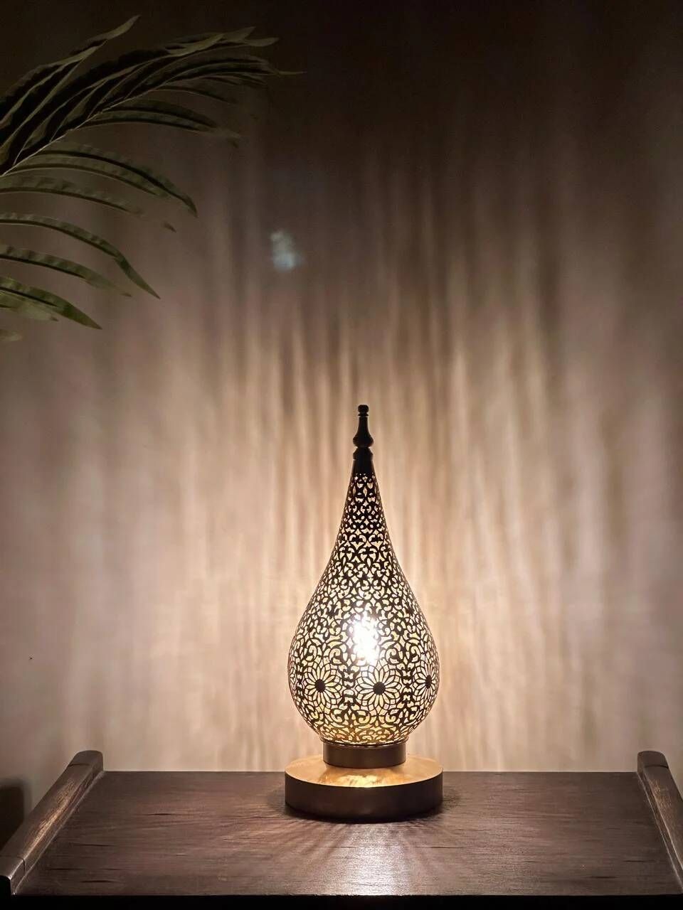 Handmade brass table lamp with a perforated drop-shaped shade.