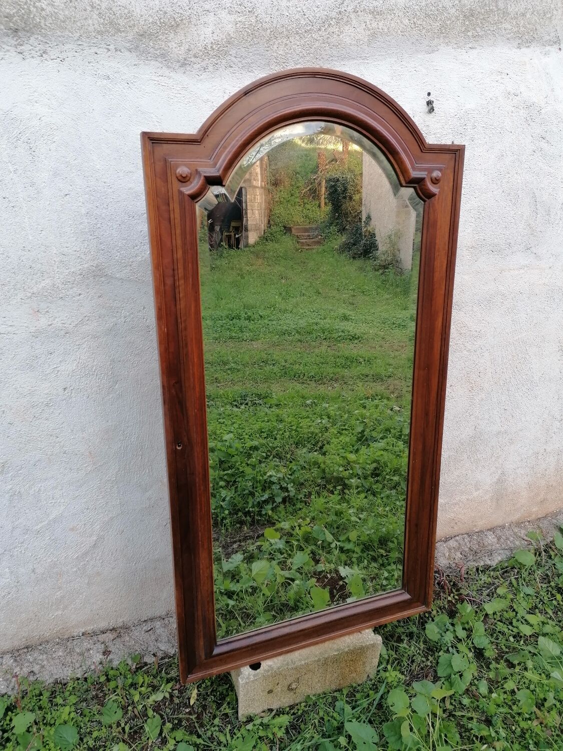 Old beveled solid wood mirror of a cabinet door.