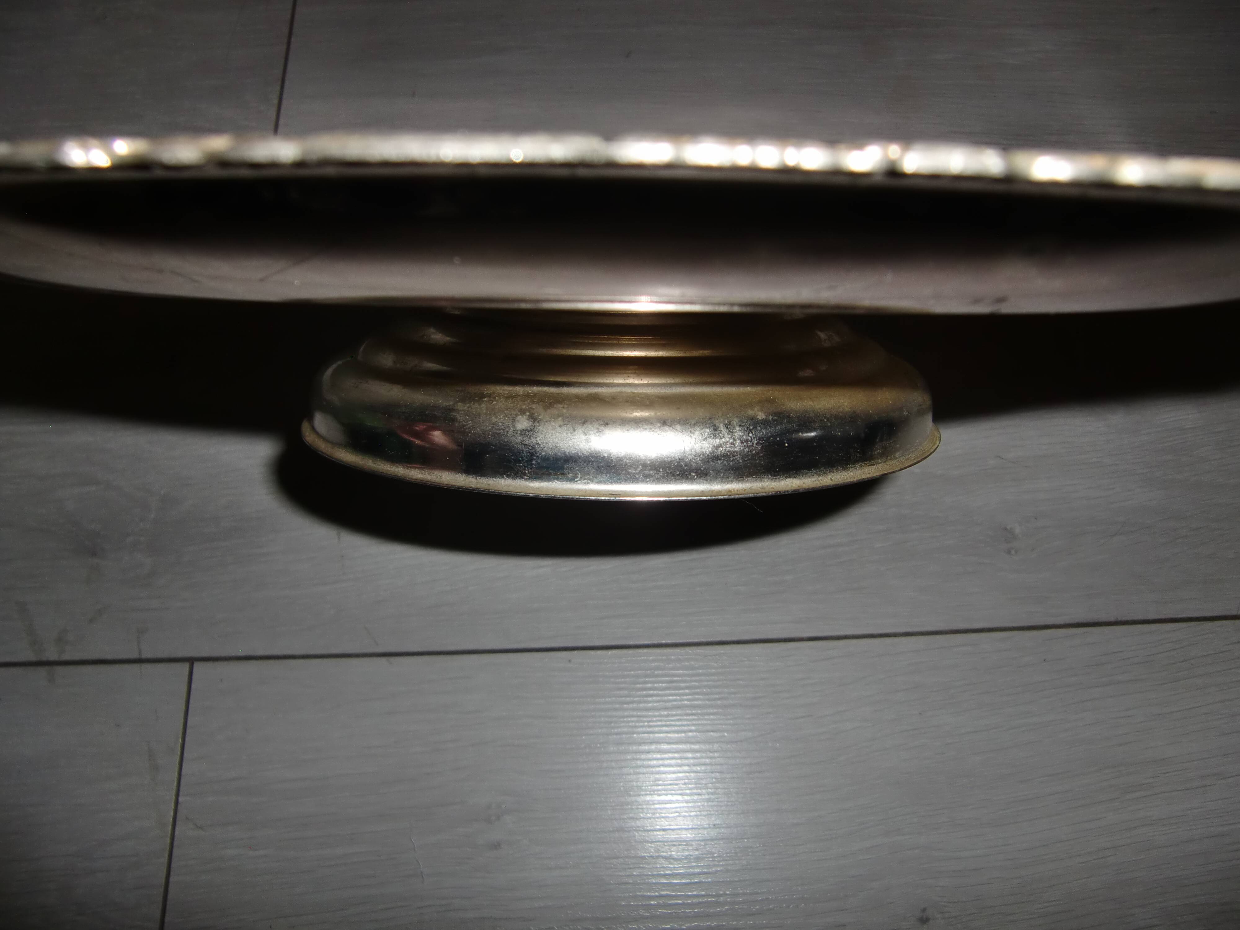 Large silver metal tray raised by a central foot