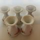 Five old egg cups with orange and grey flowers, polygonal base.