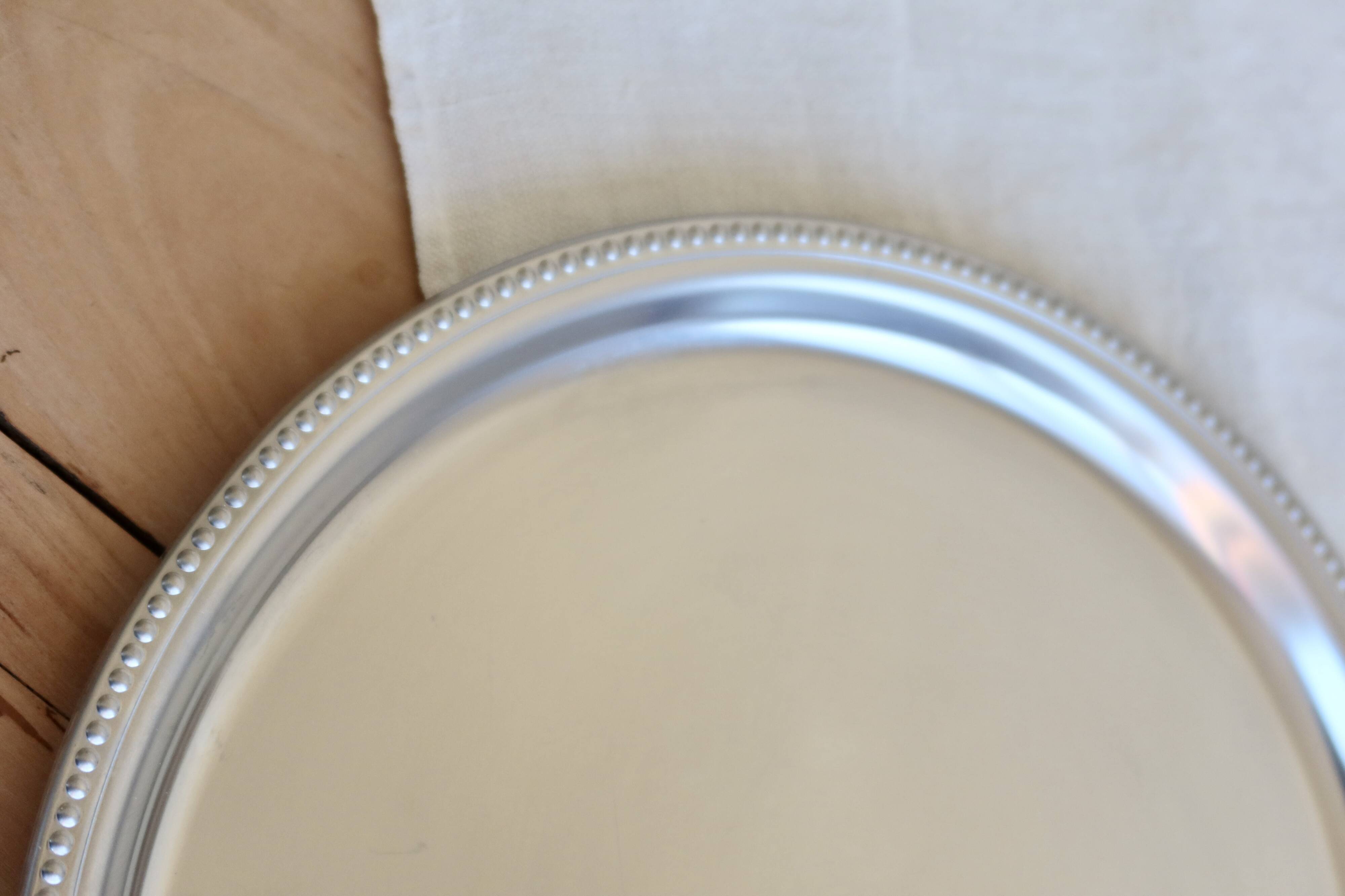 Vintage round metal plate with silver trim and beads.
