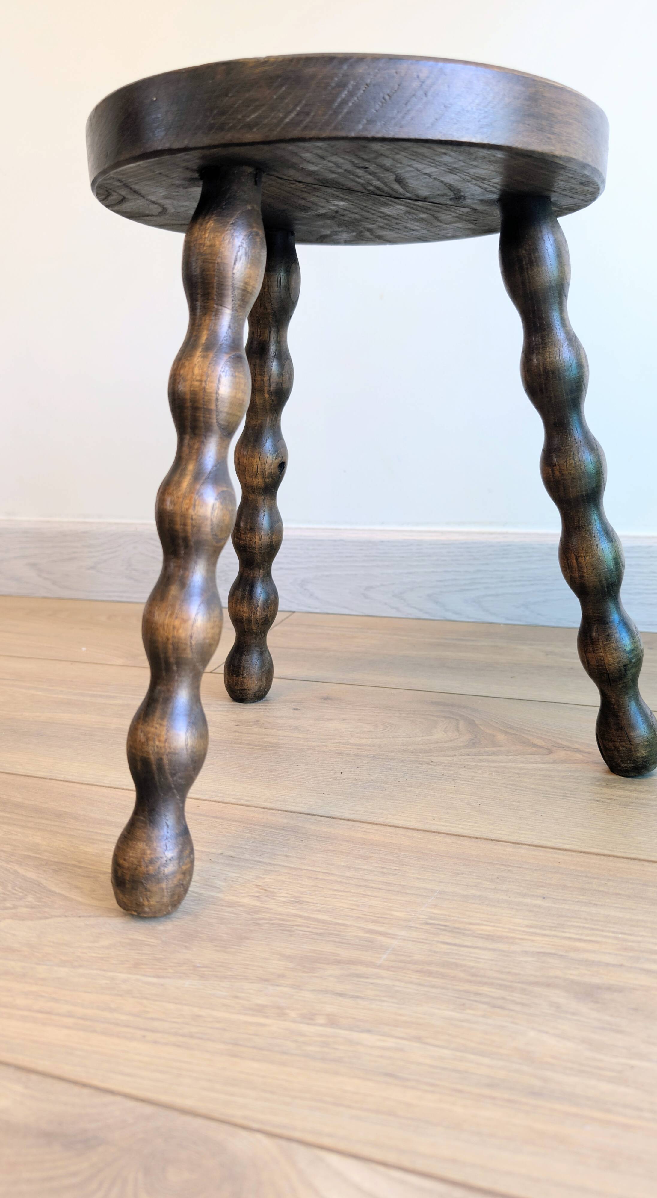 Small wooden tripod stool with turned legs, country style.