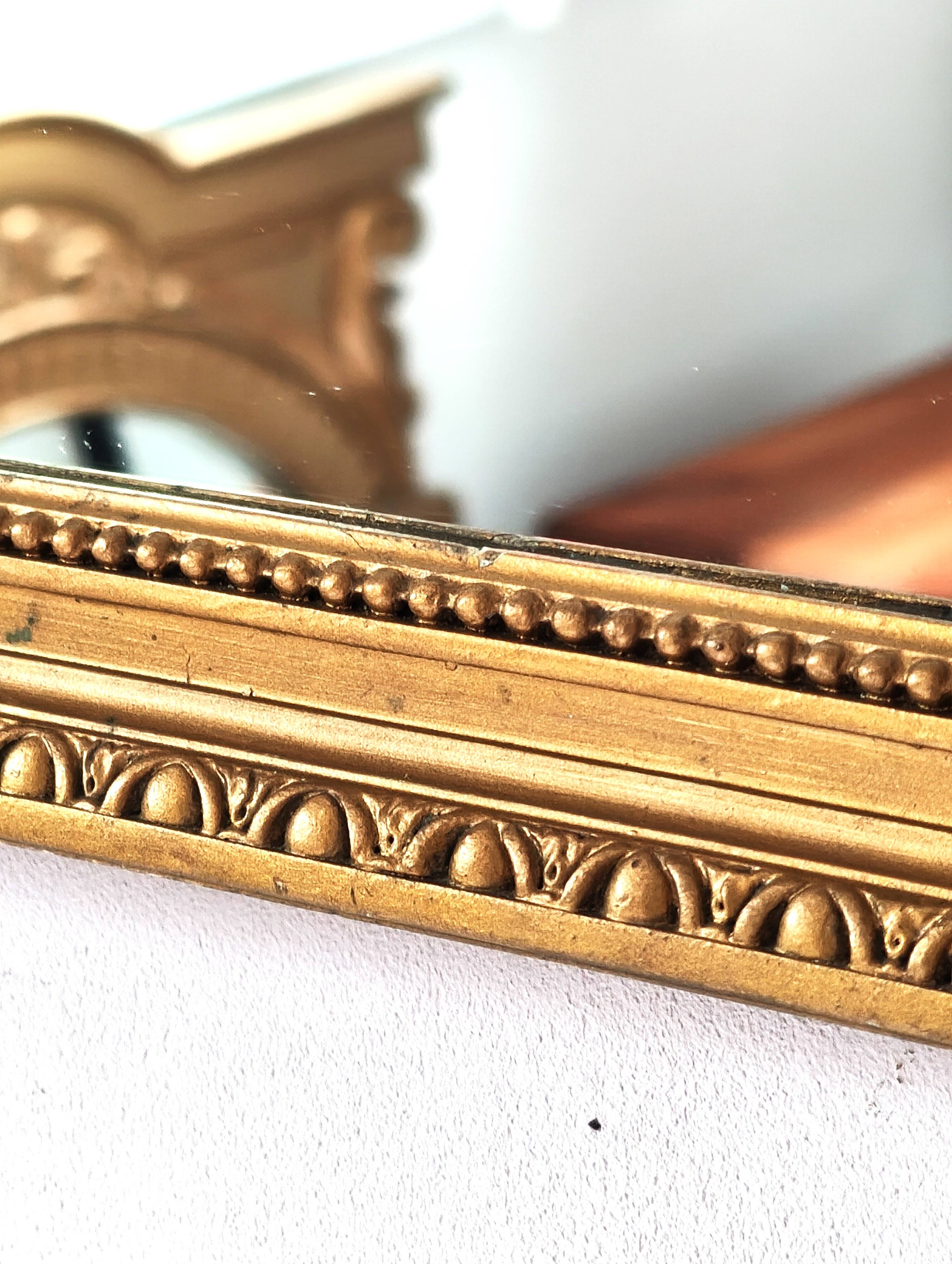 Antique mirror with a gilded frame and beaded border.