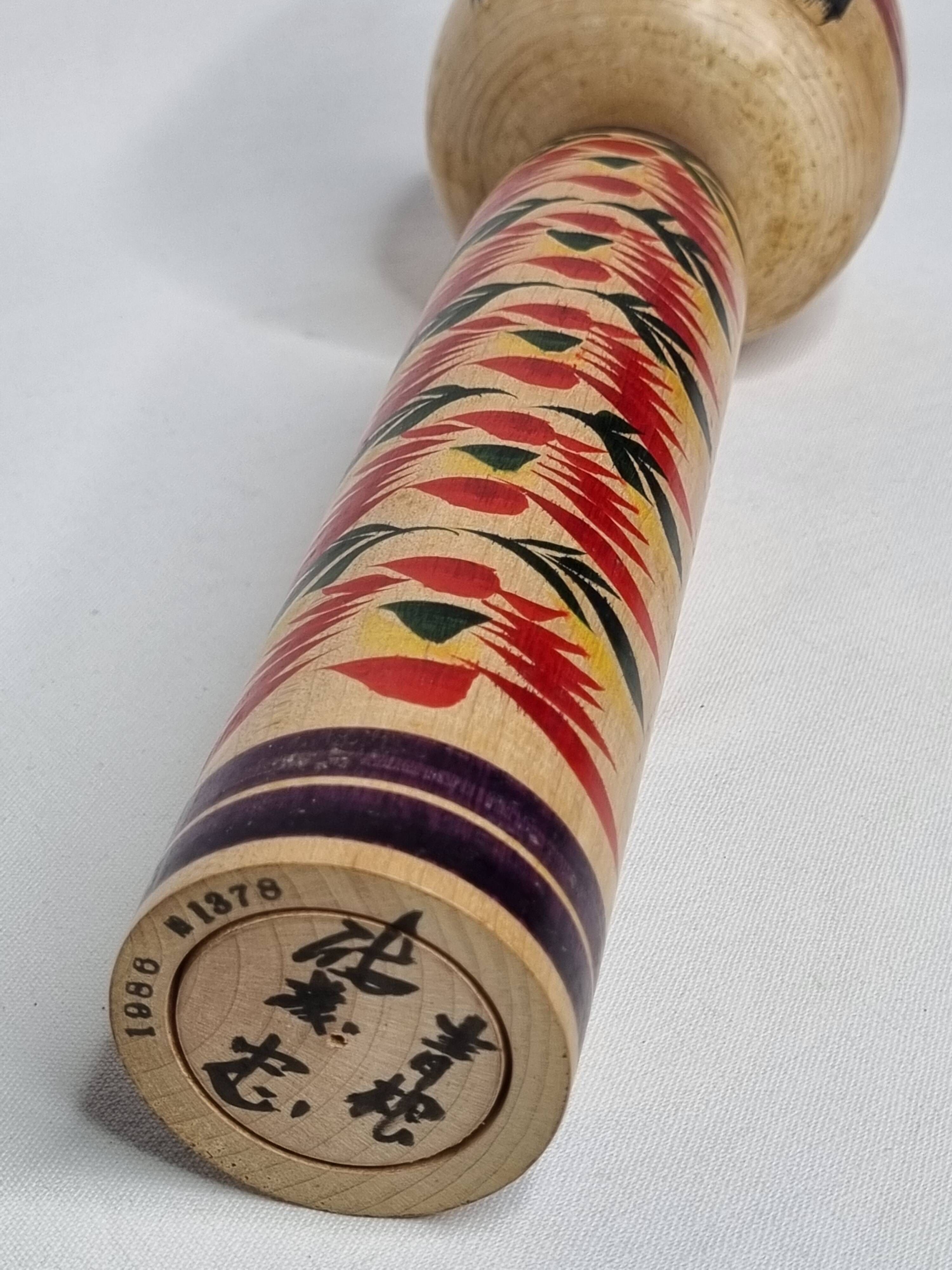 Japanese Kokeshi doll dated 1986, signed and numbered, hand-painted multi-colored floral decoration,