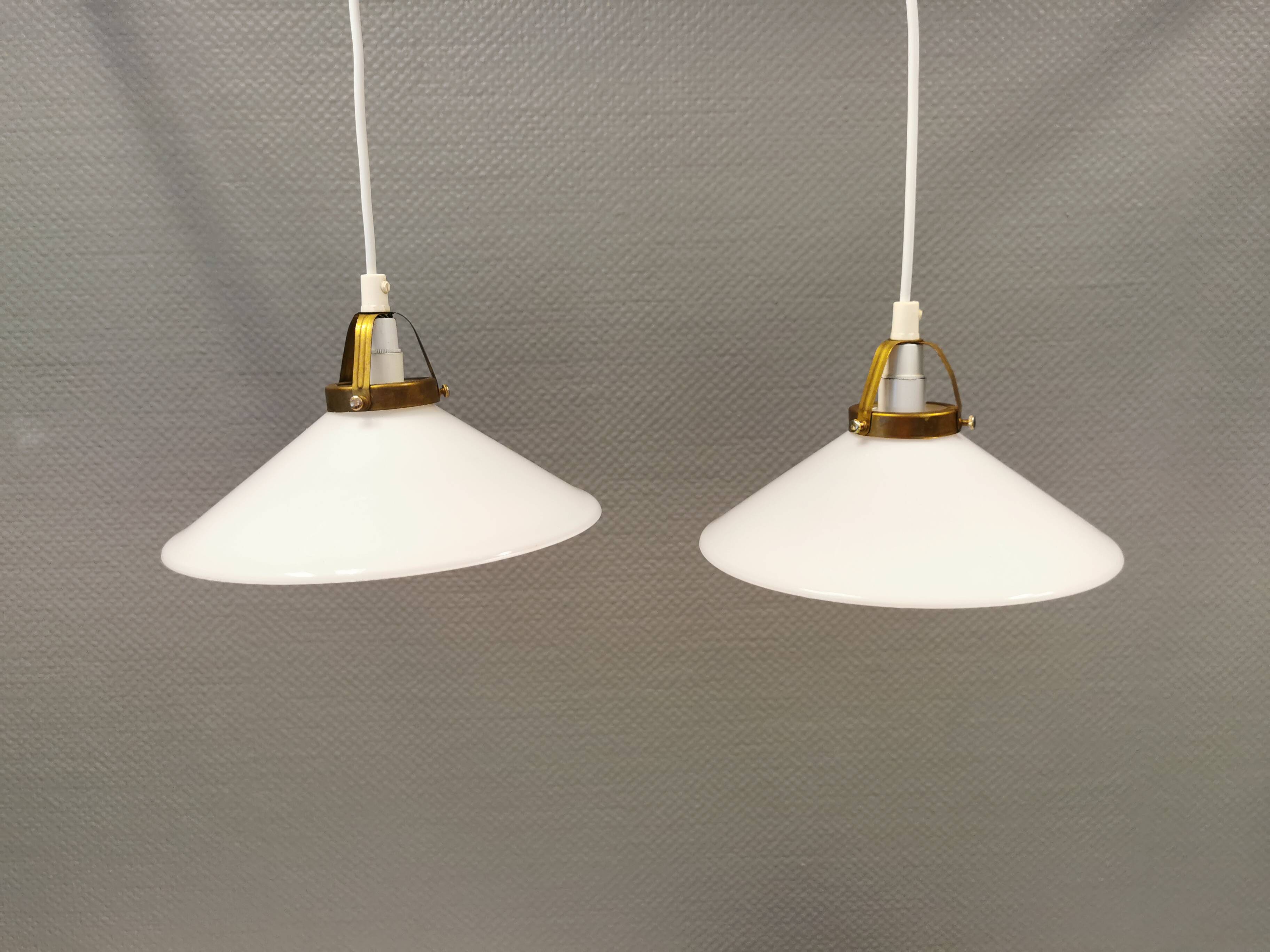 A set of hanging lamps in milky white opal glass with brass top.