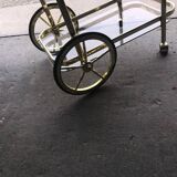 Two-tier bar cart in gold-plated brass with transparent glass shelves, yellow finish.