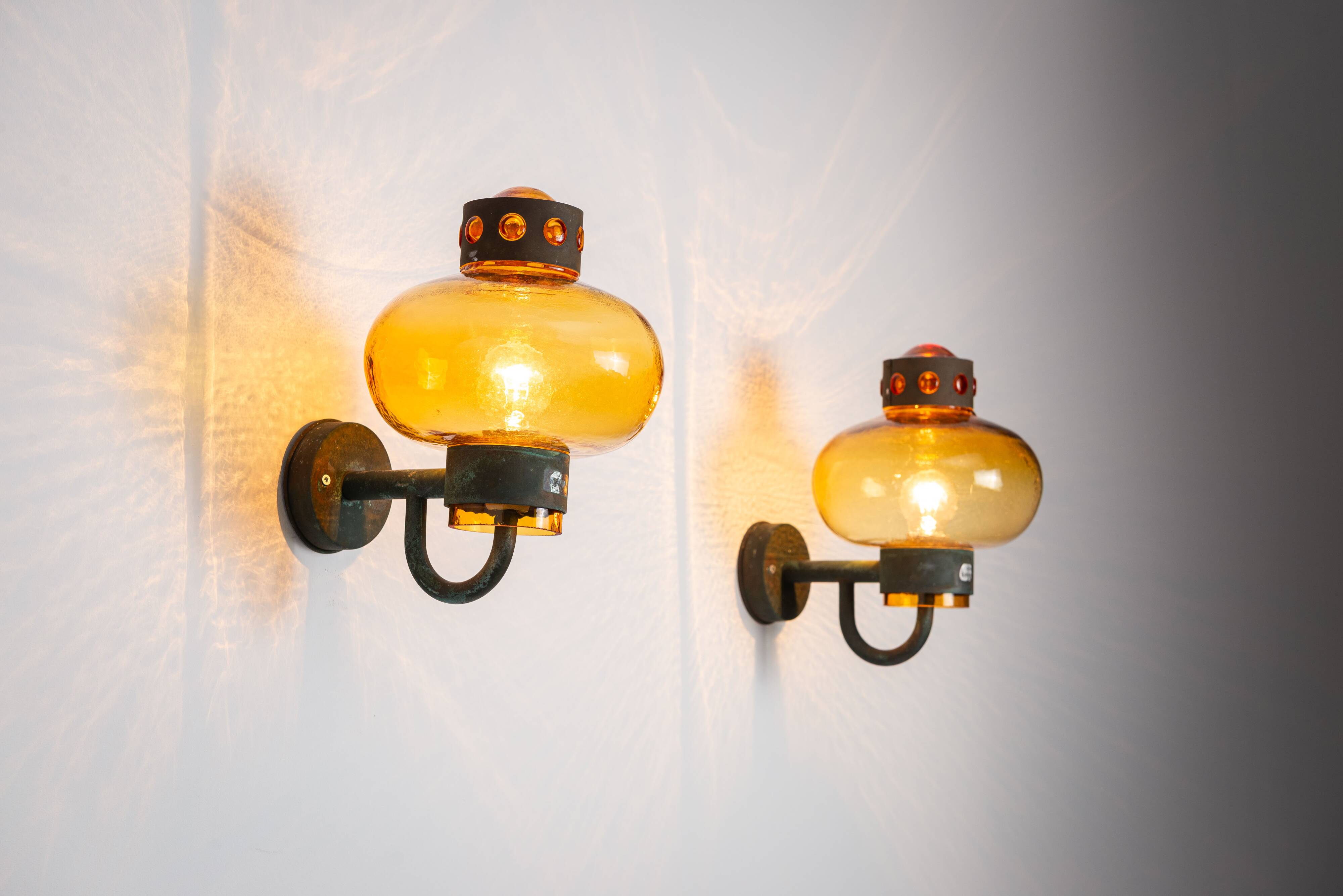 Pair of brass wall lamps with decorated amber coloured shades