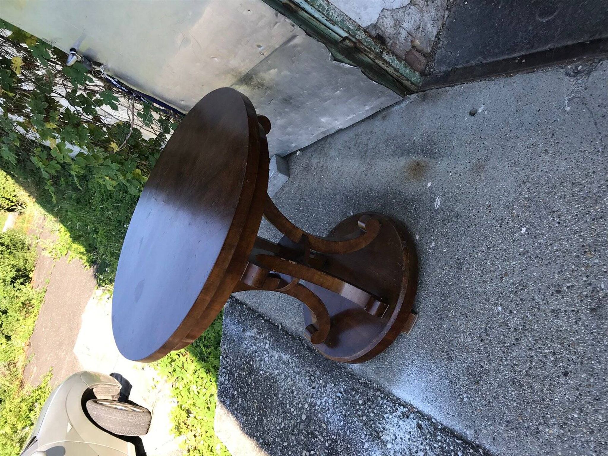 Art Deco side table in brown walnut, round top and scroll legs, France 1930s.