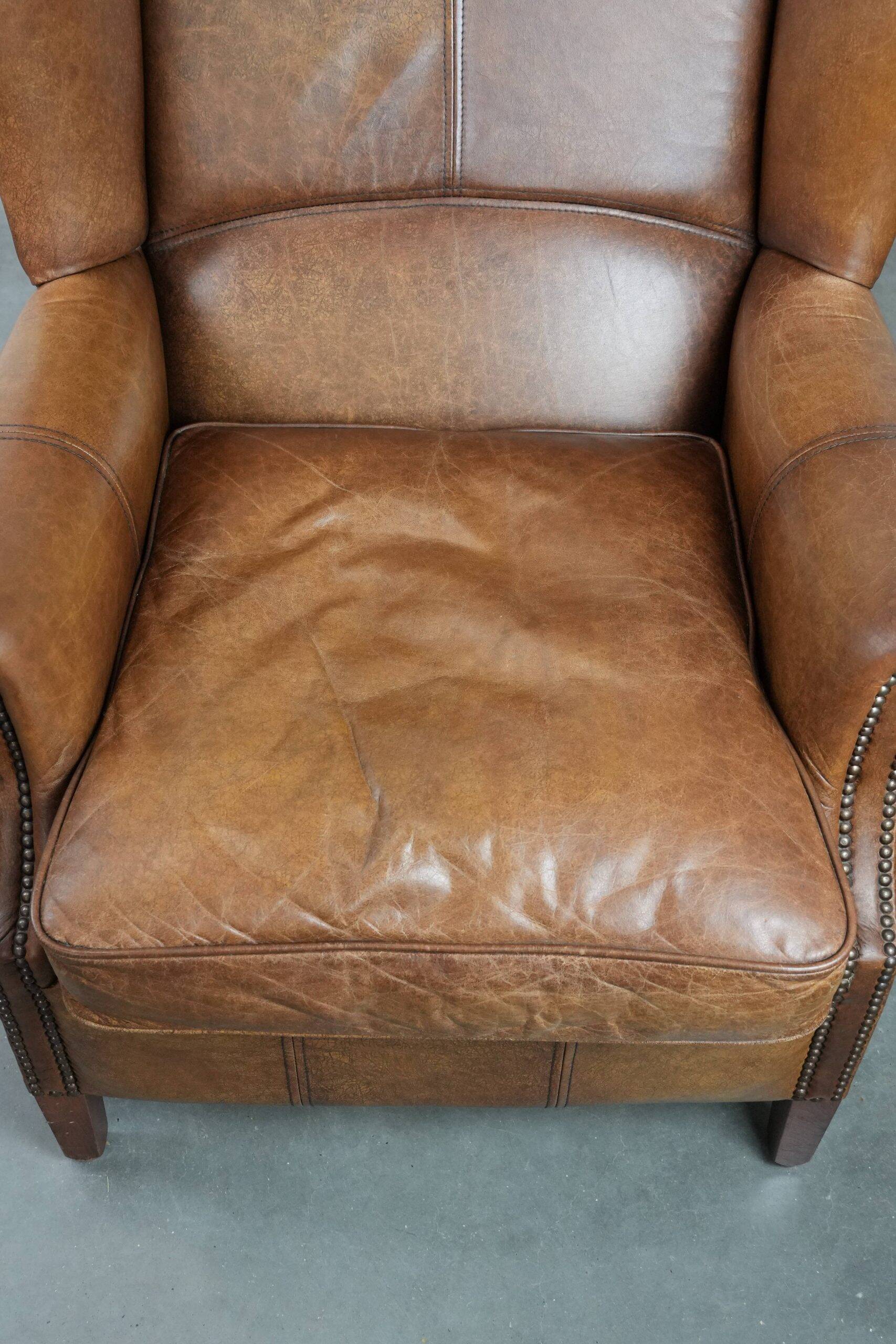 Cognac-coloured wingback armchair in English style made of cowhide leather