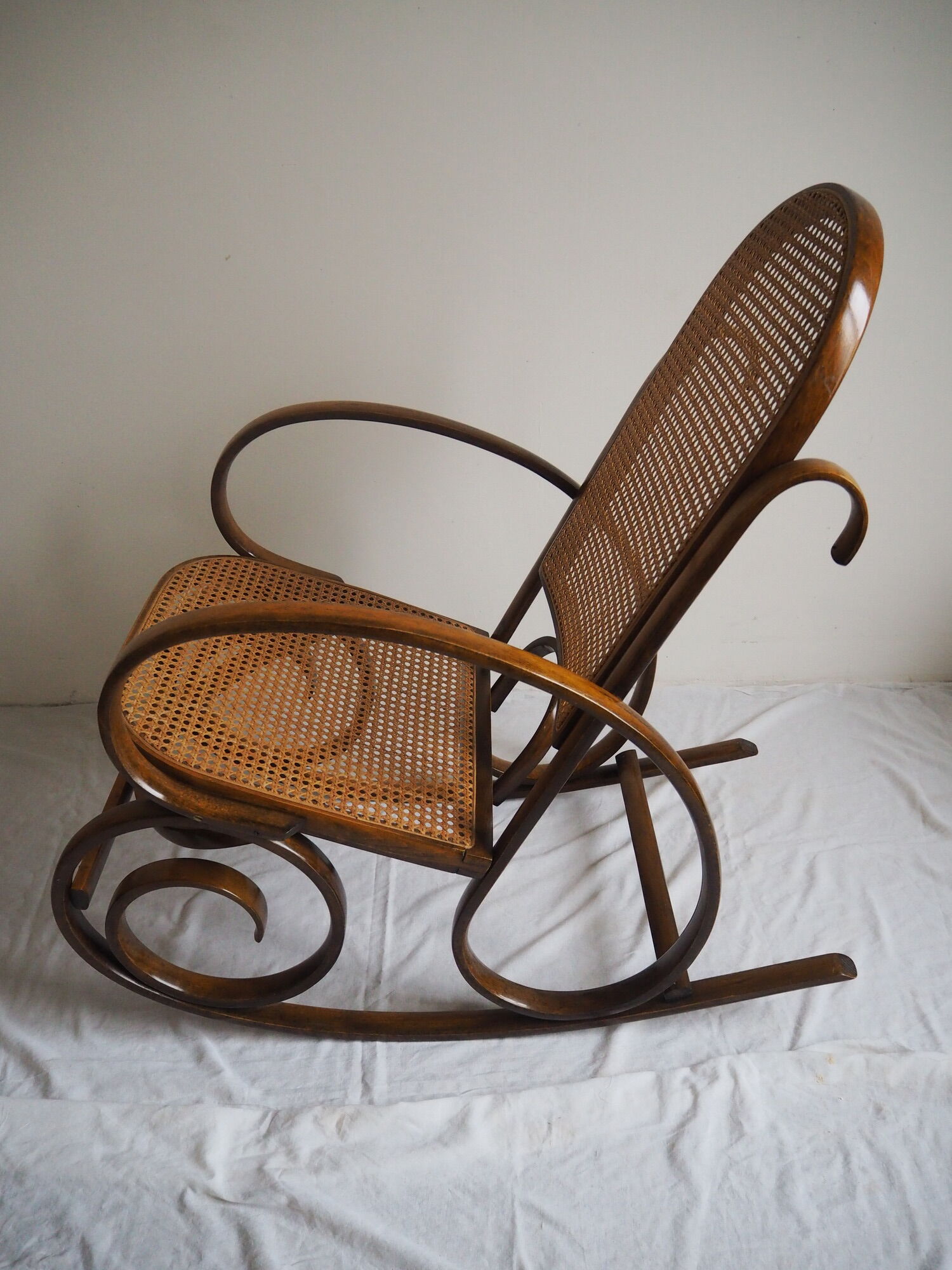 Rocking-chair en bois teinté et assise cannée