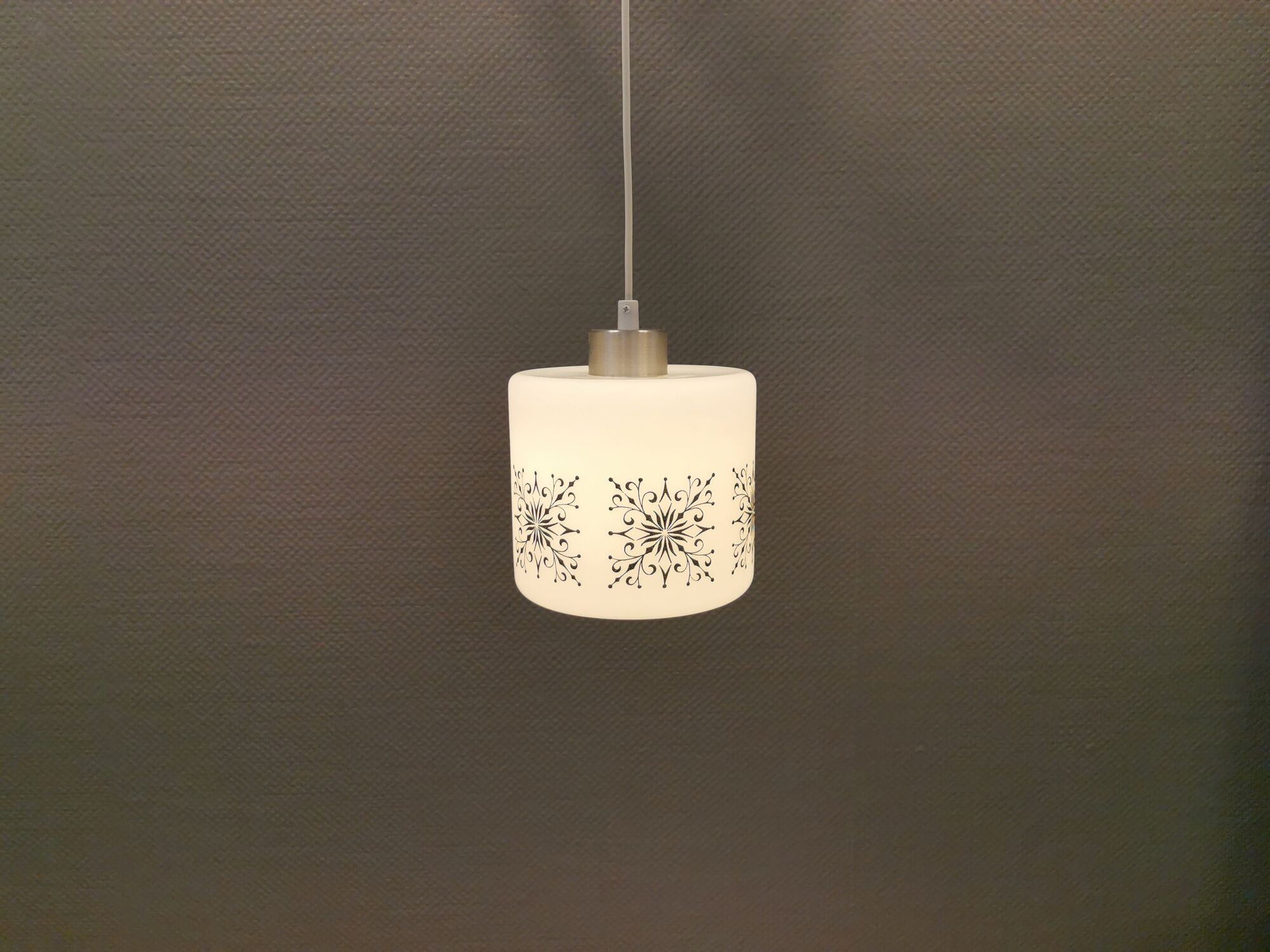 Scandinavian hanging lamp in white glass with inlayed black motifs.