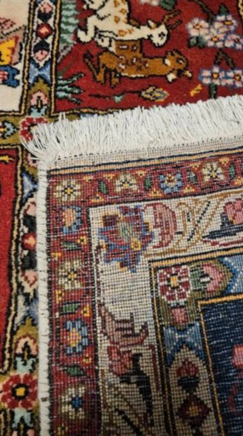 Handmade Persian carpet, featuring animal and plant motifs.