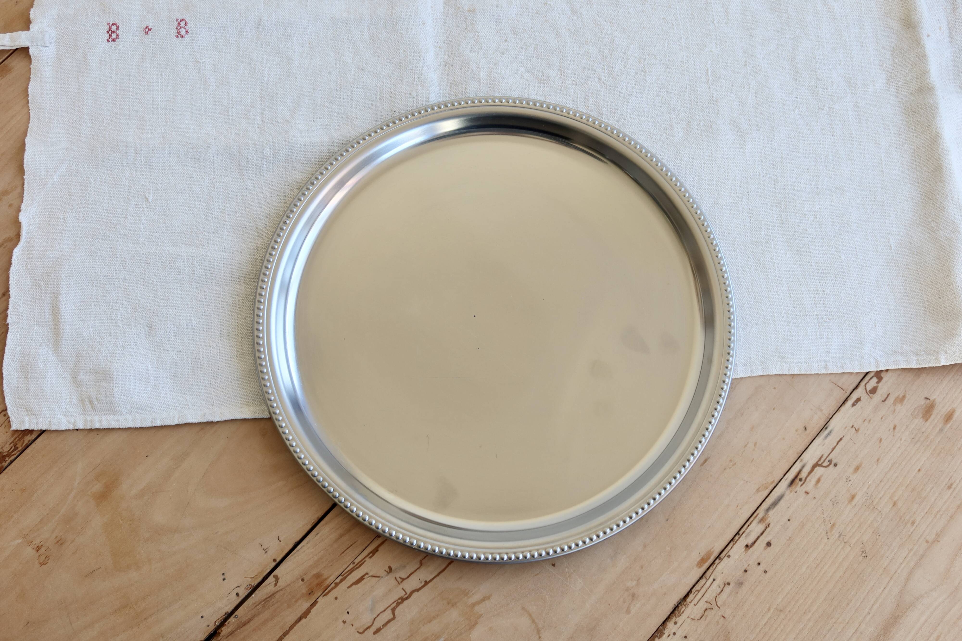 Vintage round metal plate with silver trim and beads.