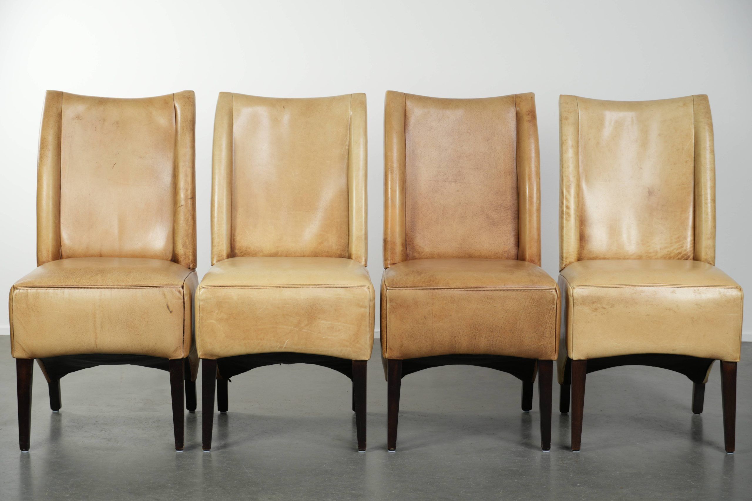 Ensemble de quatre chaises de salle à manger en cuir de vache avec un siège confortable et un dossier haut.