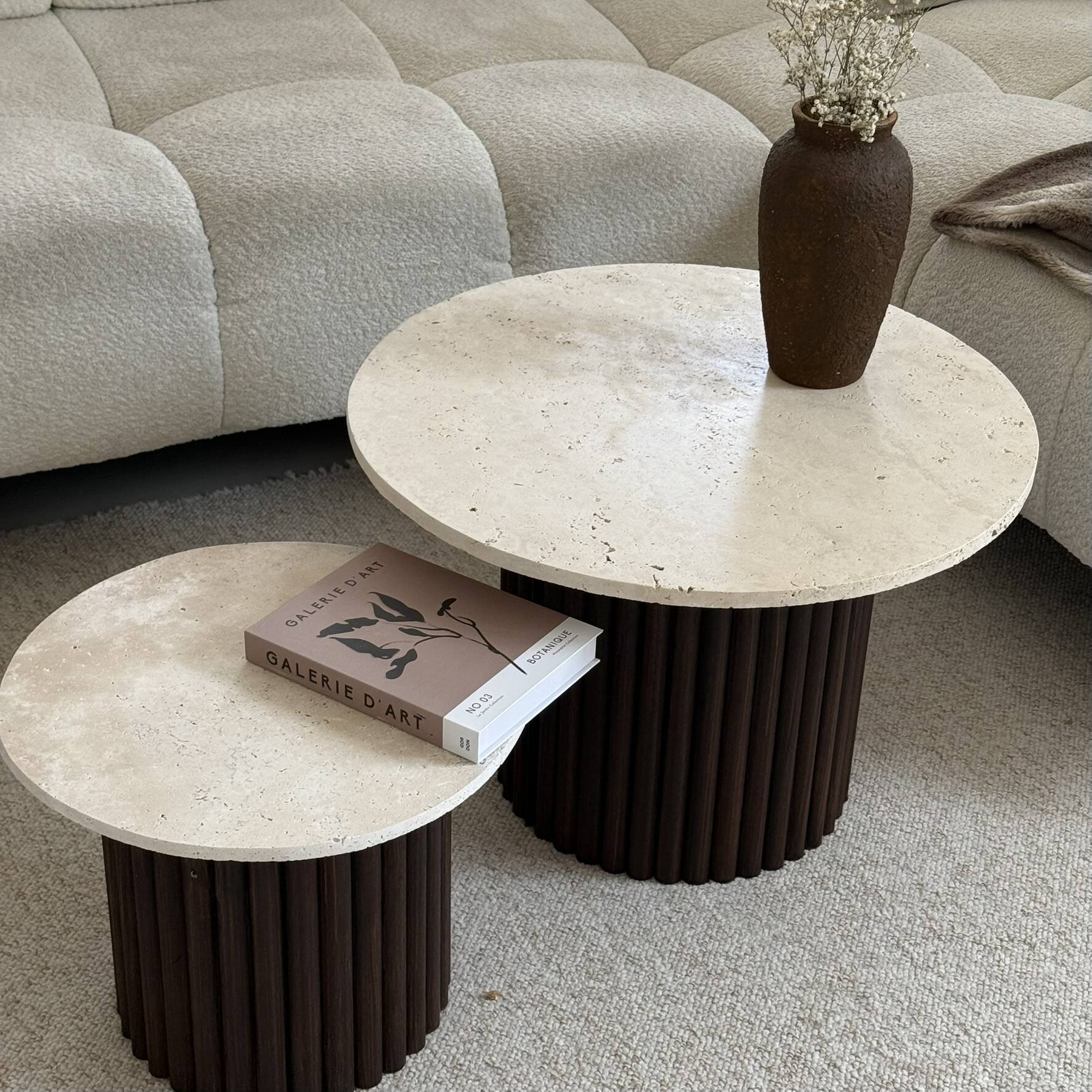 Round nesting coffee table in travertine and dark fluted wood.