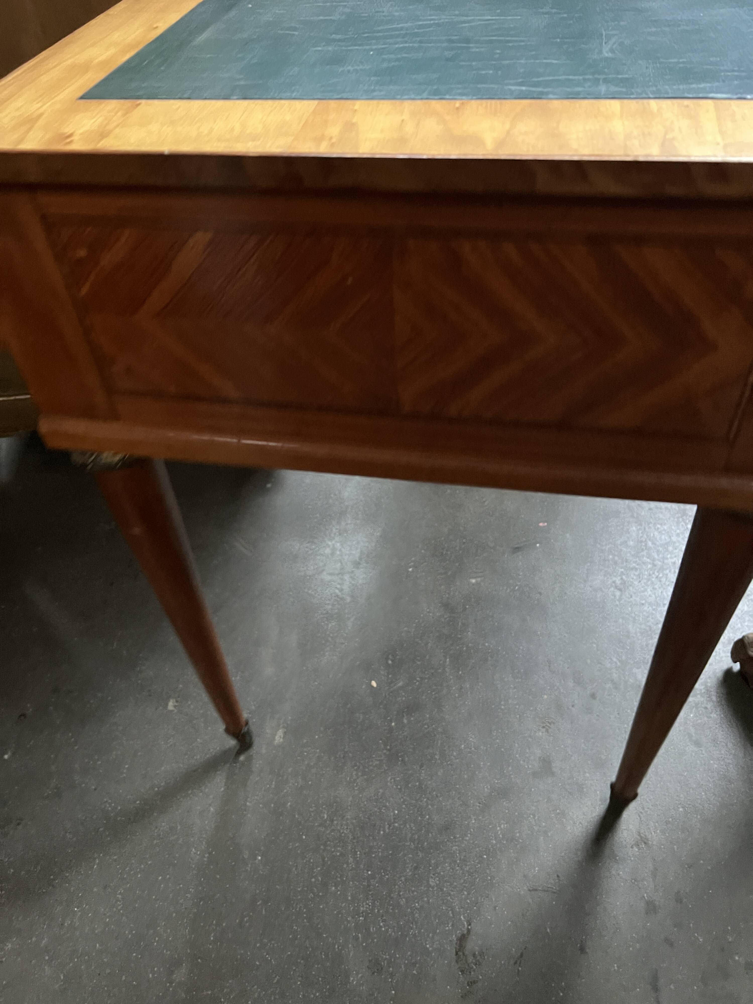 Louis XVI style marquetry desk. The top is decorated with green leather.