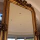 French palace mirror with bow and lion heads, gilded frame.