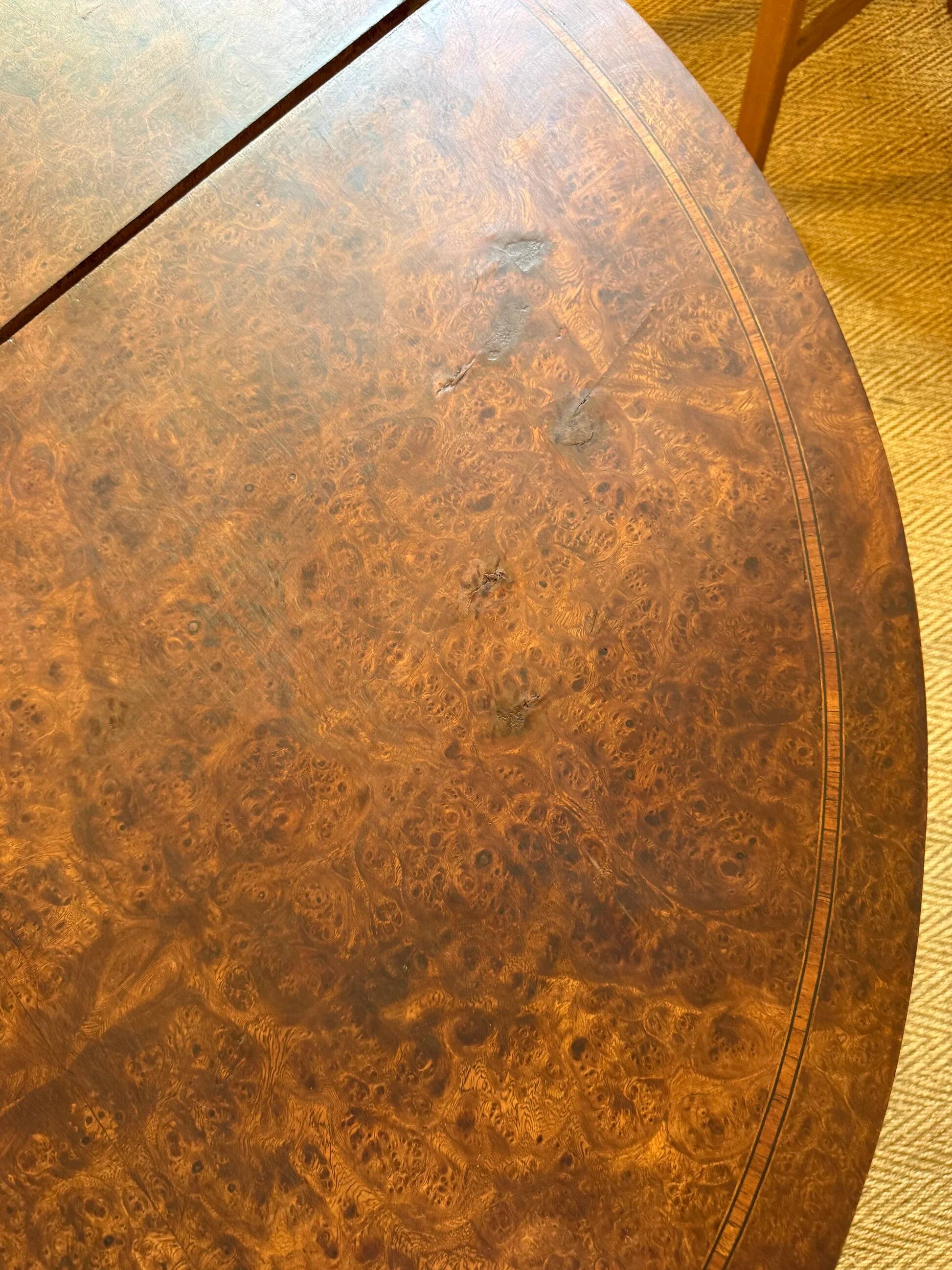 Oval extendable dining table in wood and walnut burl veneer.