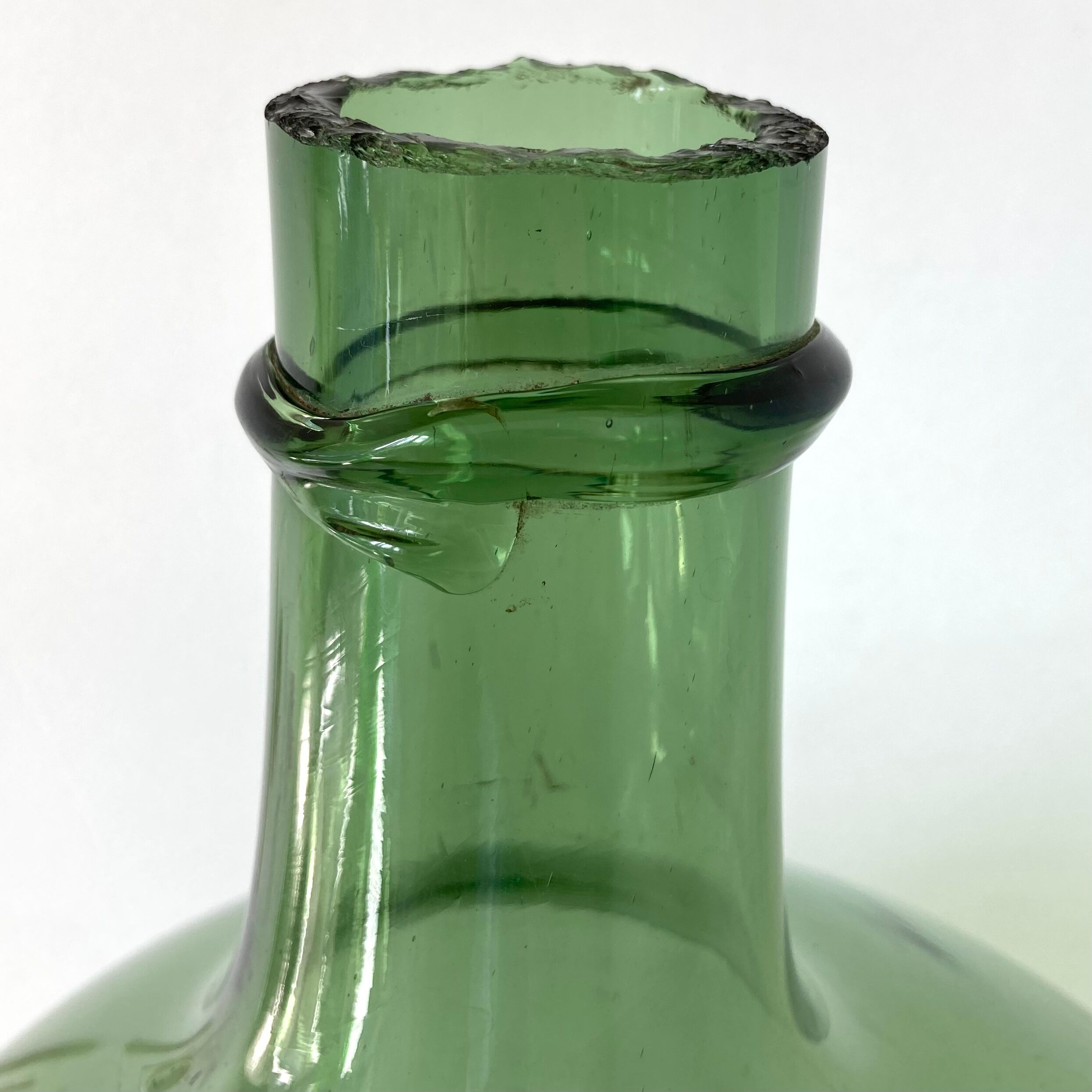 Old demijohn in green glass with ringed neck and hammered opening
