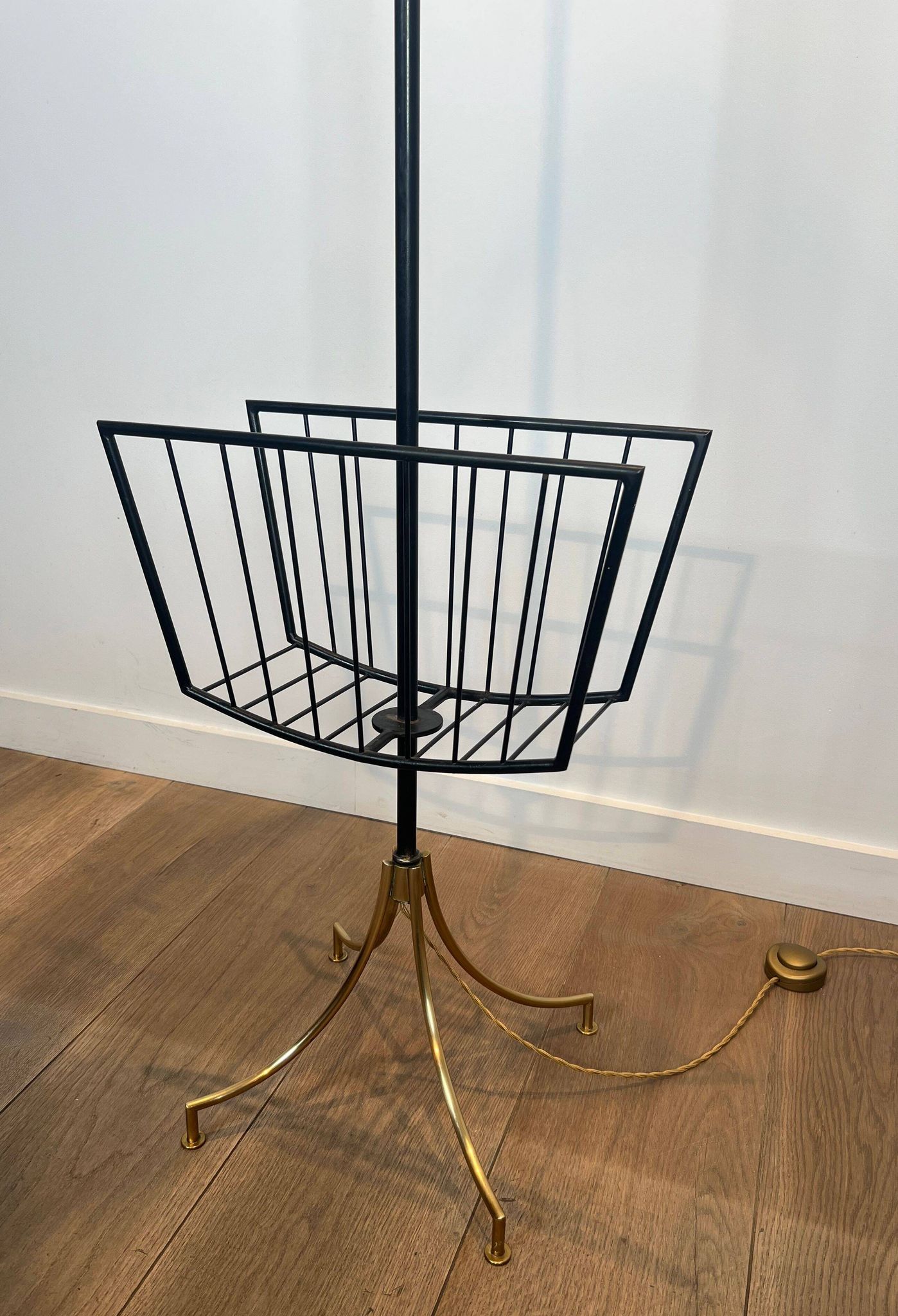 Designer floor lamp in black lacquered metal and brass, incorporating a magazine rack