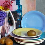 Seven pastel-colored plates mixed with vintage earthenware
