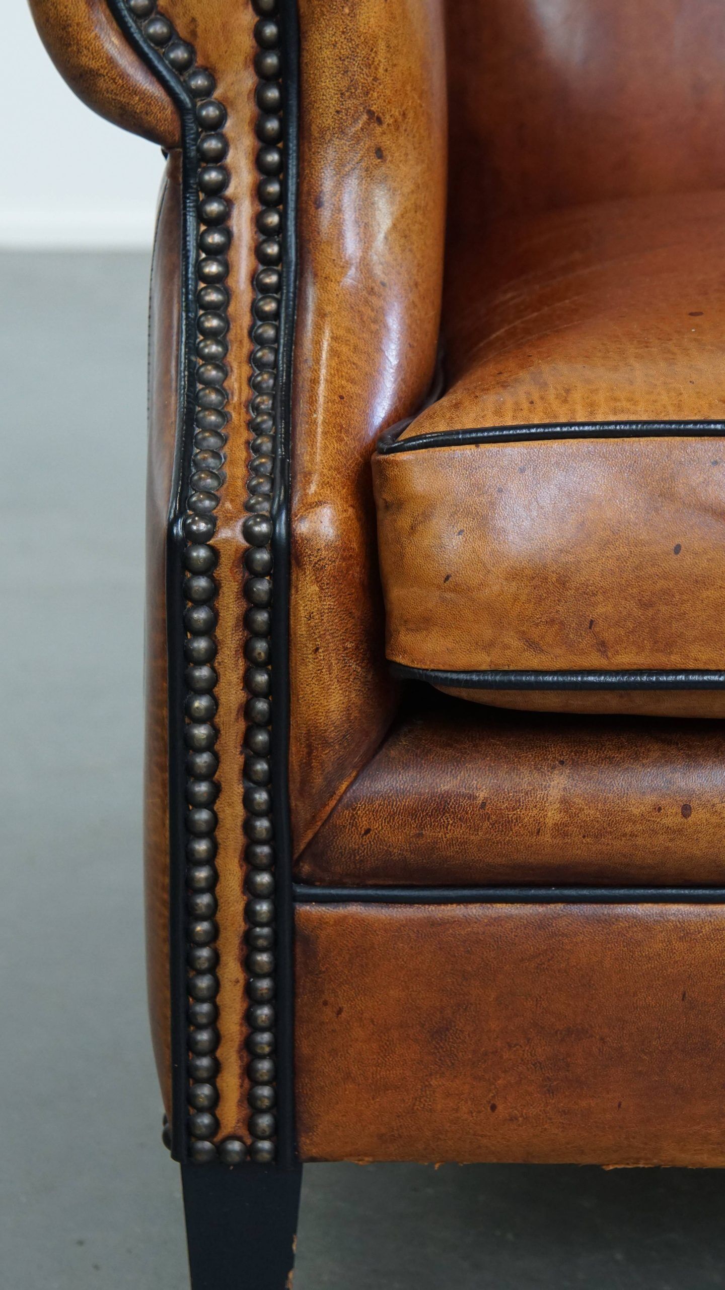 Sheepskin wingback armchair with stitching and black piping