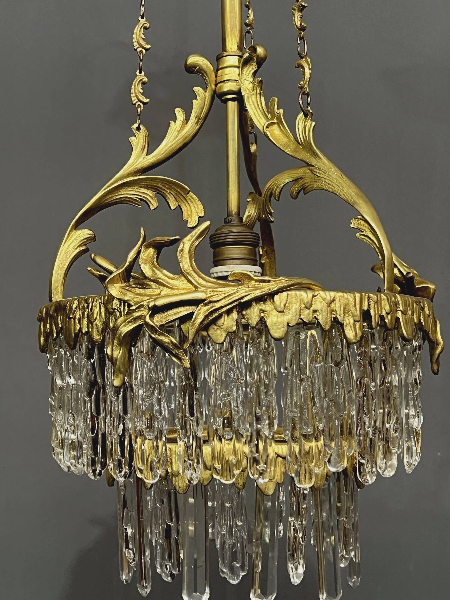 Antique chandelier in gilded bronze with crystal pendants.