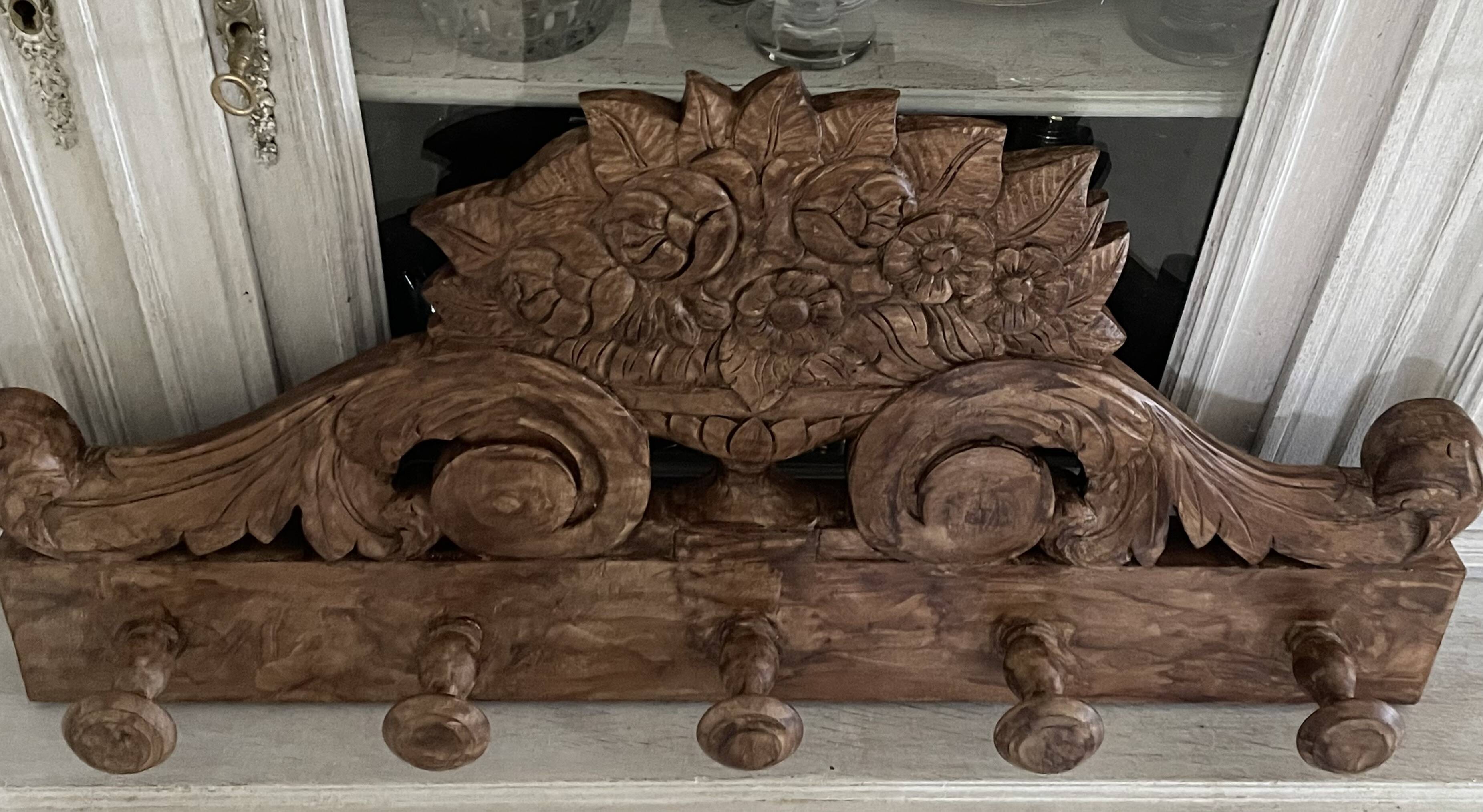 Wall-mounted coat rack on a carved wooden pediment