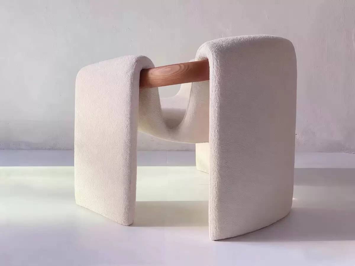 Sculptural lounge armchair in ecru boucle fabric with solid wood details.