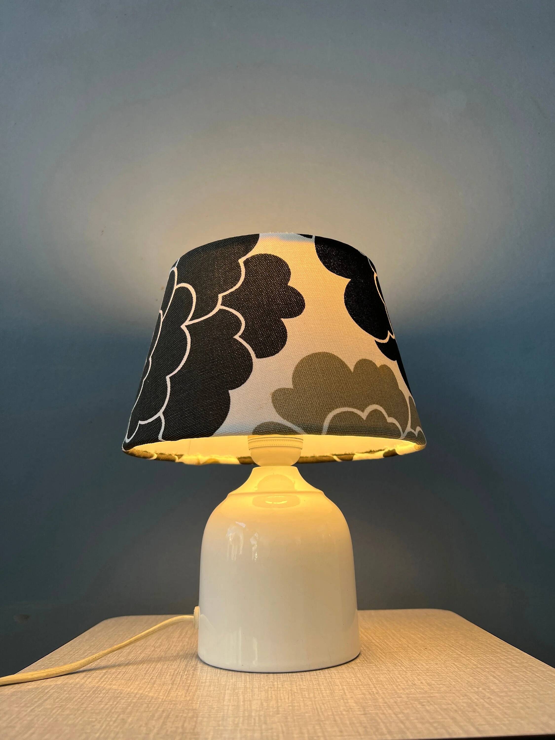 Small Space Age table lamp with a porcelain base and black and white flower shade.