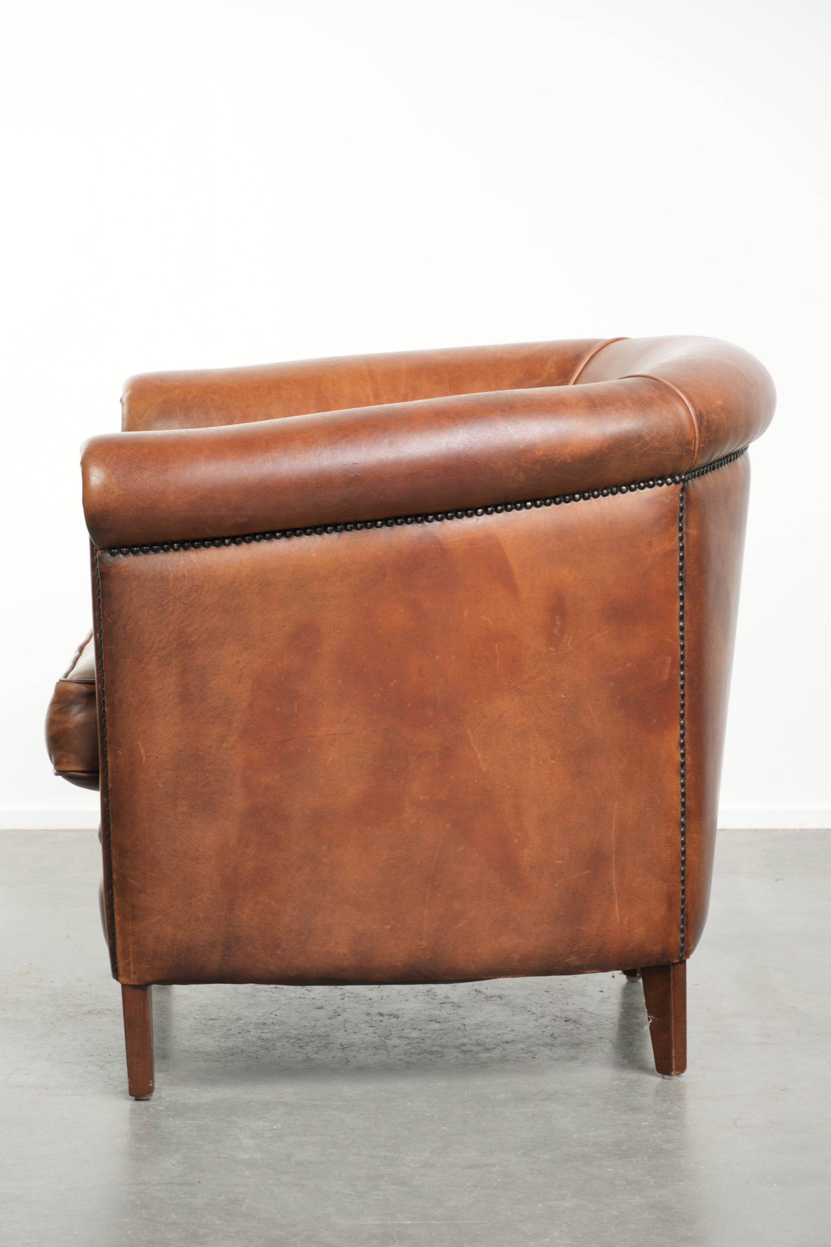 Sheepskin club armchair with a cognac colour finished with decorative nails