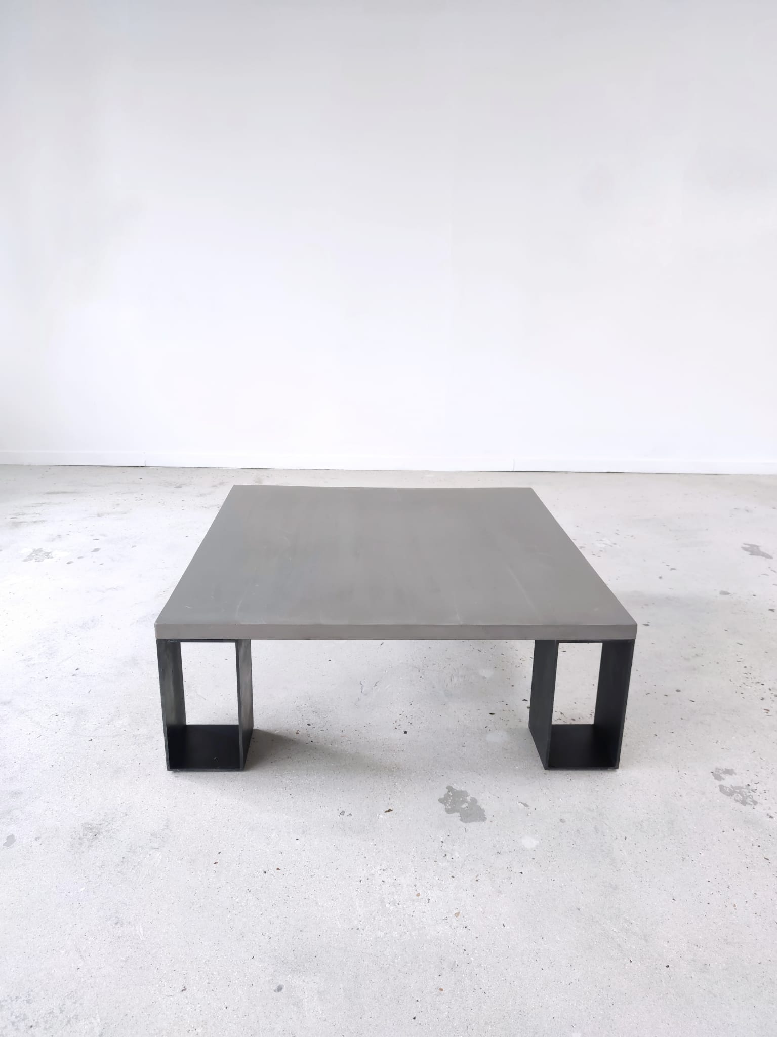 Table basse minimaliste en béton ciré et acier massif 1m20x1m20