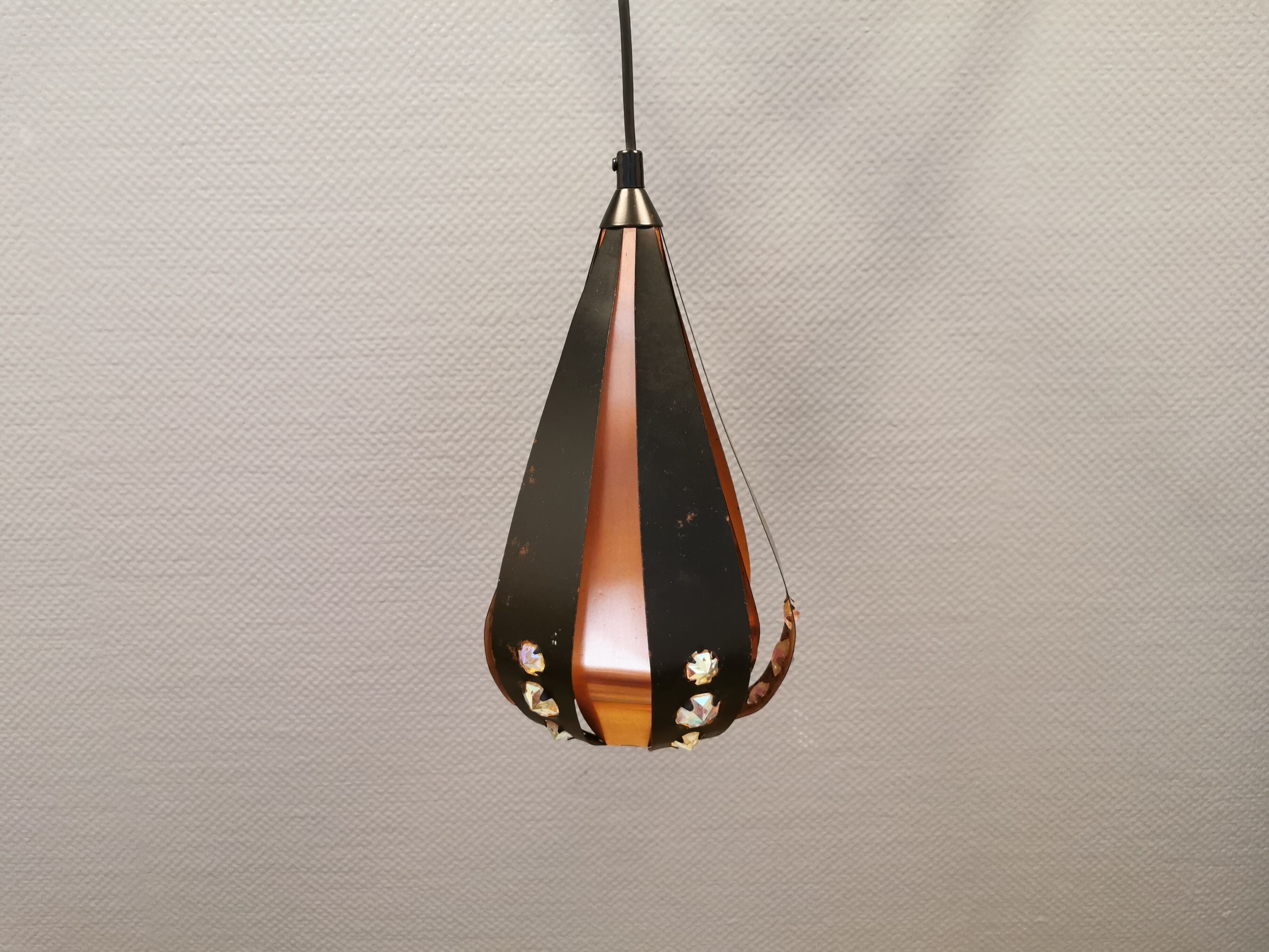 Hanging lamp in thin metal pieces, copper colored and black with prisms.